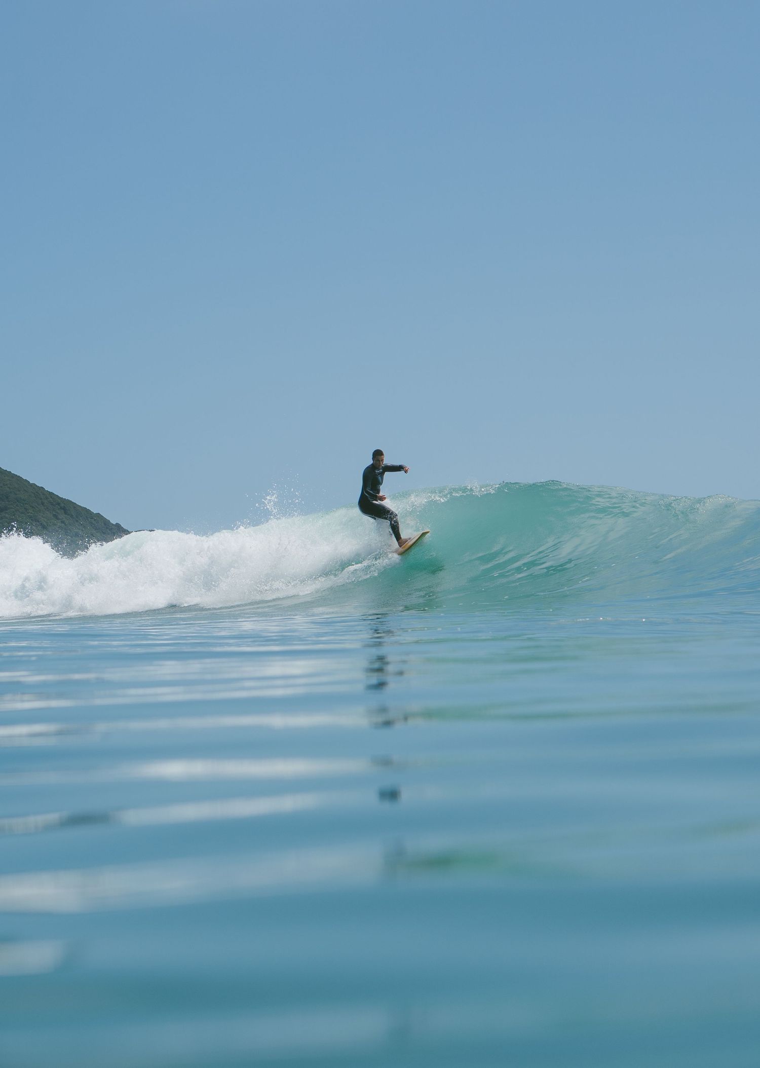 Surfer performs aerial maneuver off the lip of a breaking turquoise wave.