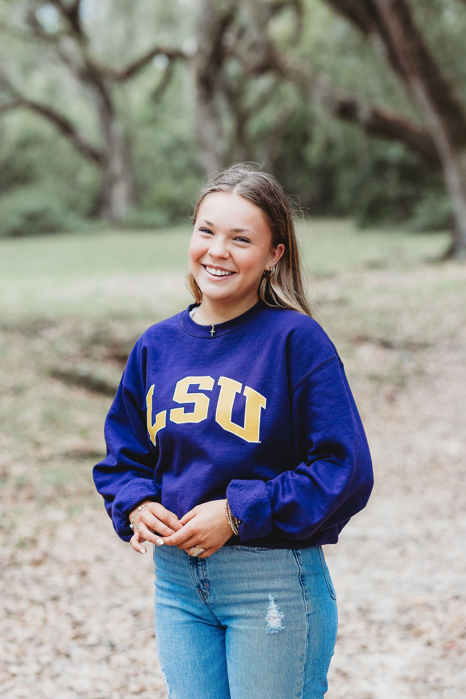 Person wearing LSU collegiate sweatshirt poses outdoors in natural setting.