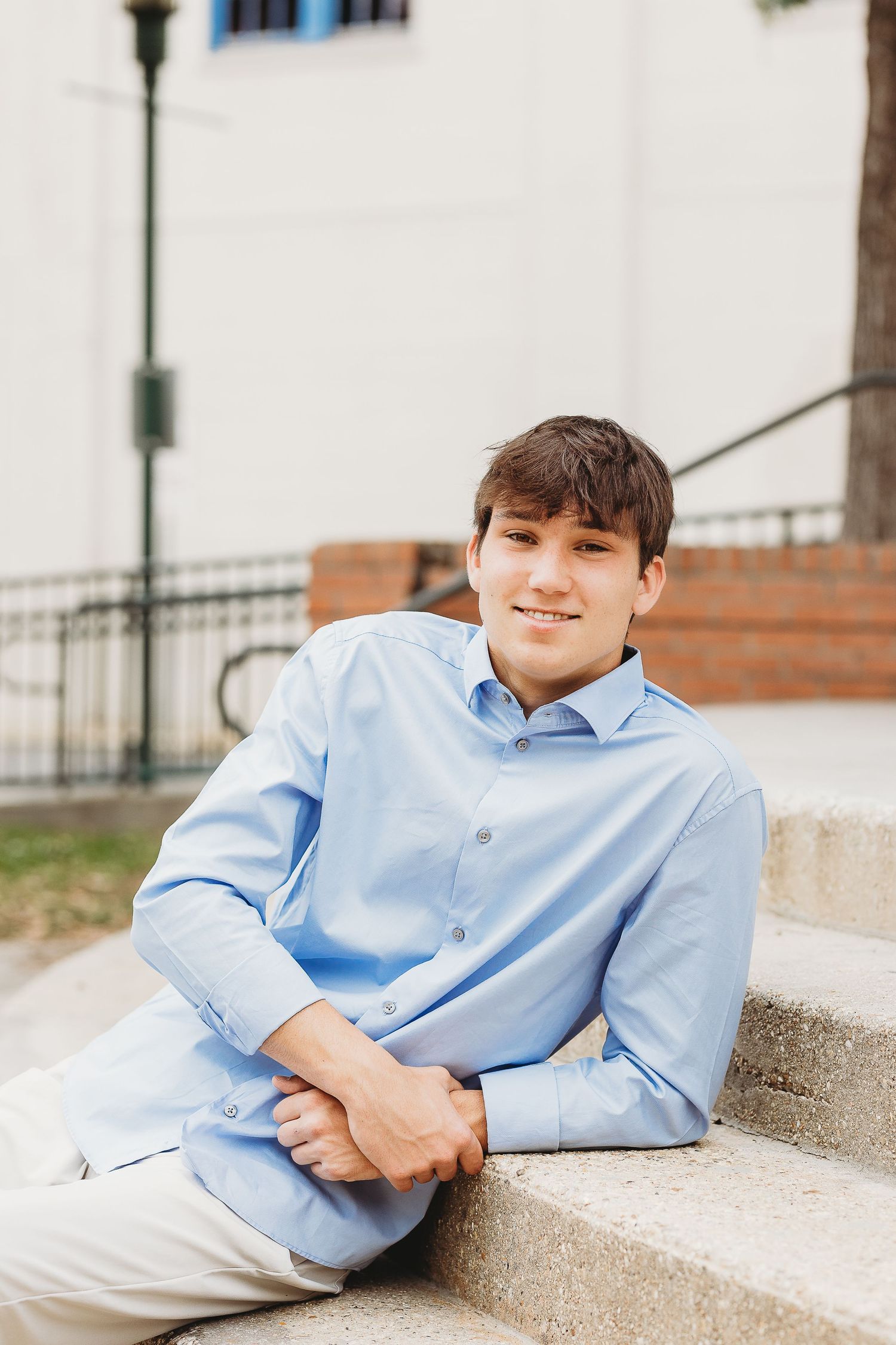 Portrait series of a person in a light blue button-down shirt reclining on concrete steps.