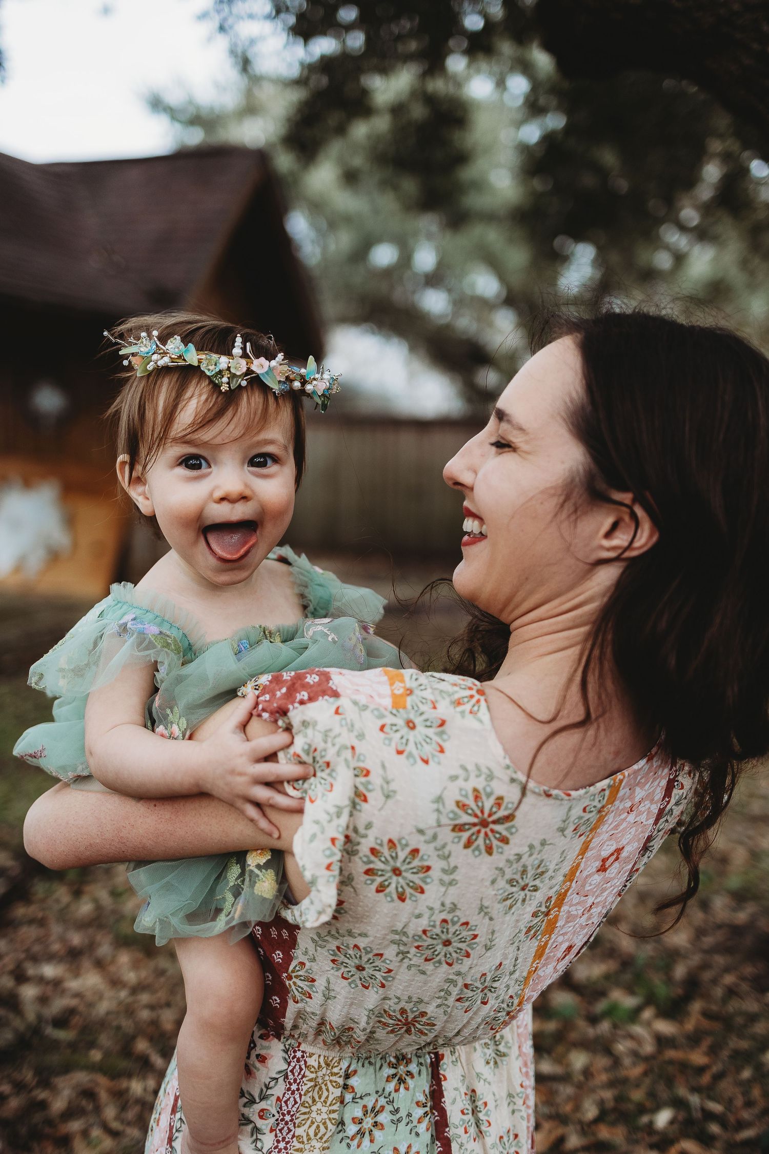 Joyful mother and baby in mint green and floral outfits playing outdoors.