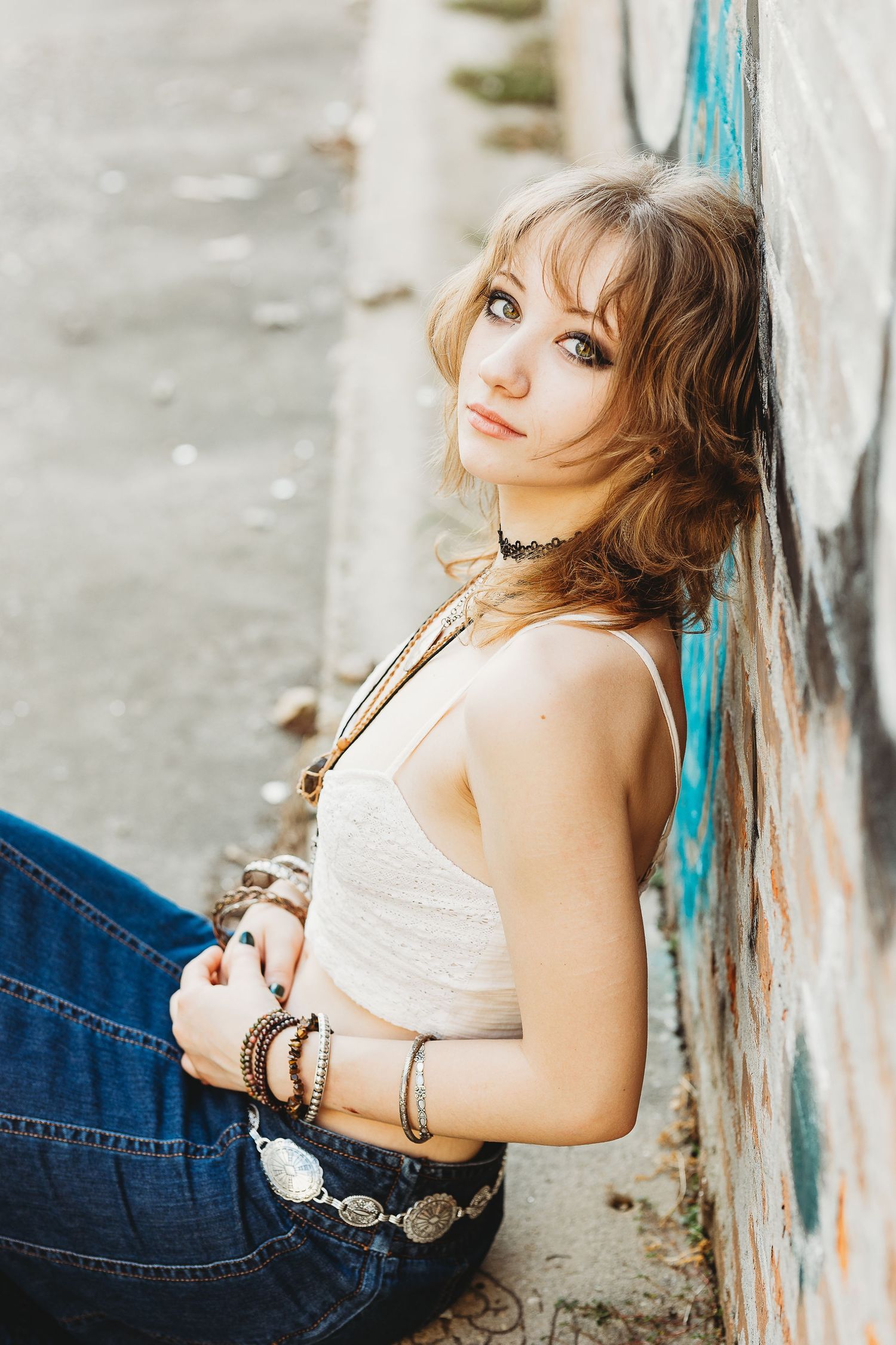 Artistic portrait against graffiti wall featuring boho style accessories and casual denim.