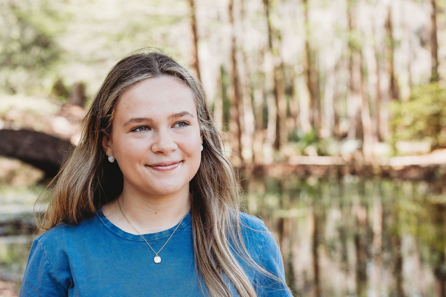 Natural outdoor portraits near water with blue top and casual style.