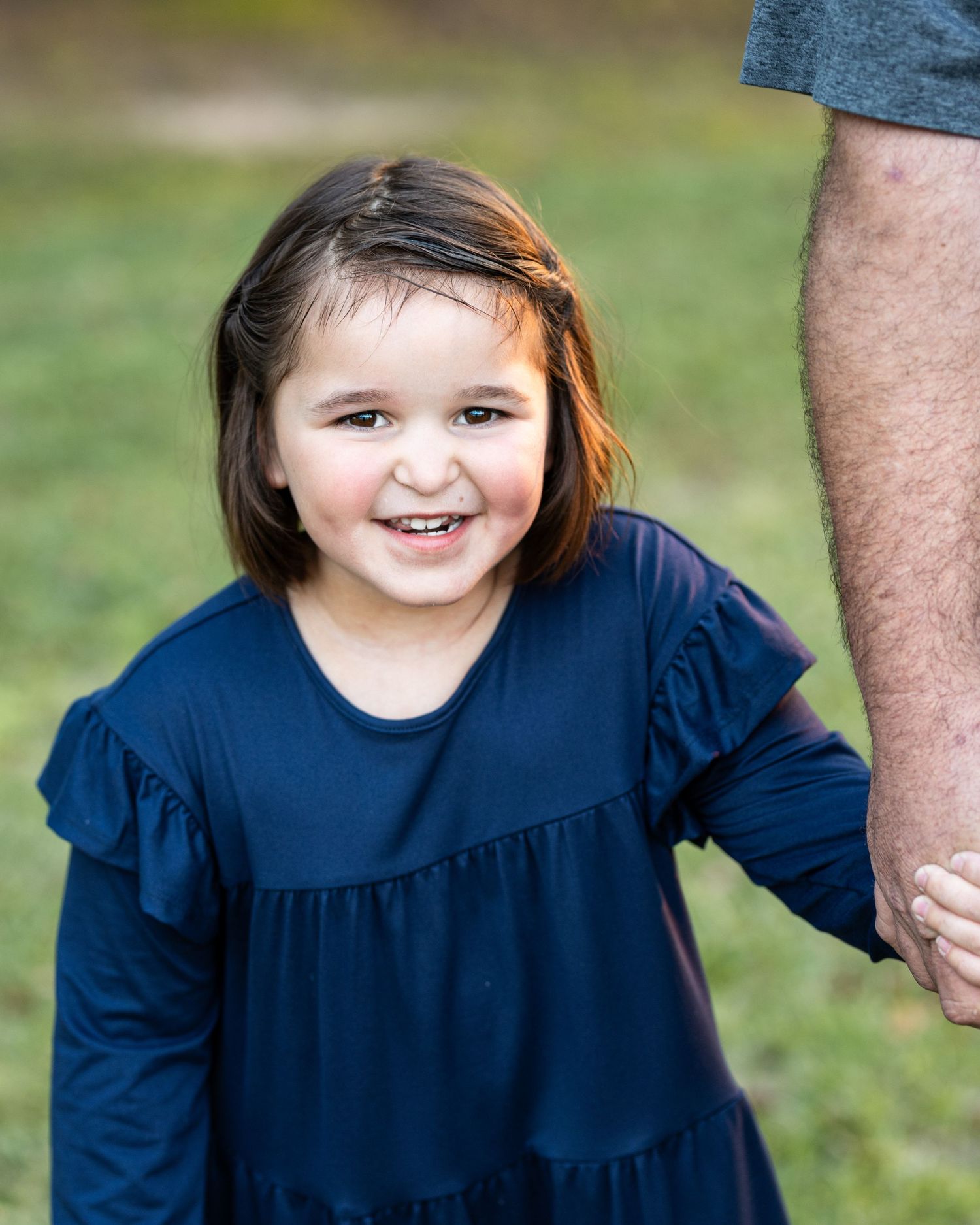 A series of five photos showing someone in a navy blue dress against a green outdoor background.