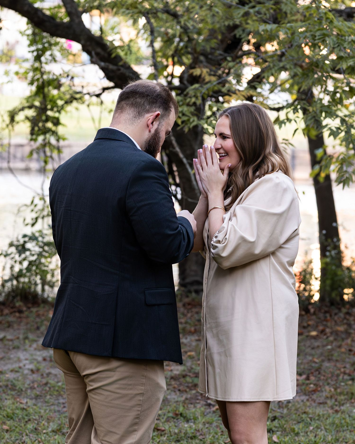 A couple shares a joyful moment during what appears to be a proposal in an outdoor garden setting.