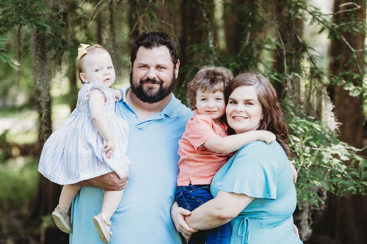 Outdoor family photo session in a lush green forest setting with natural lighting.