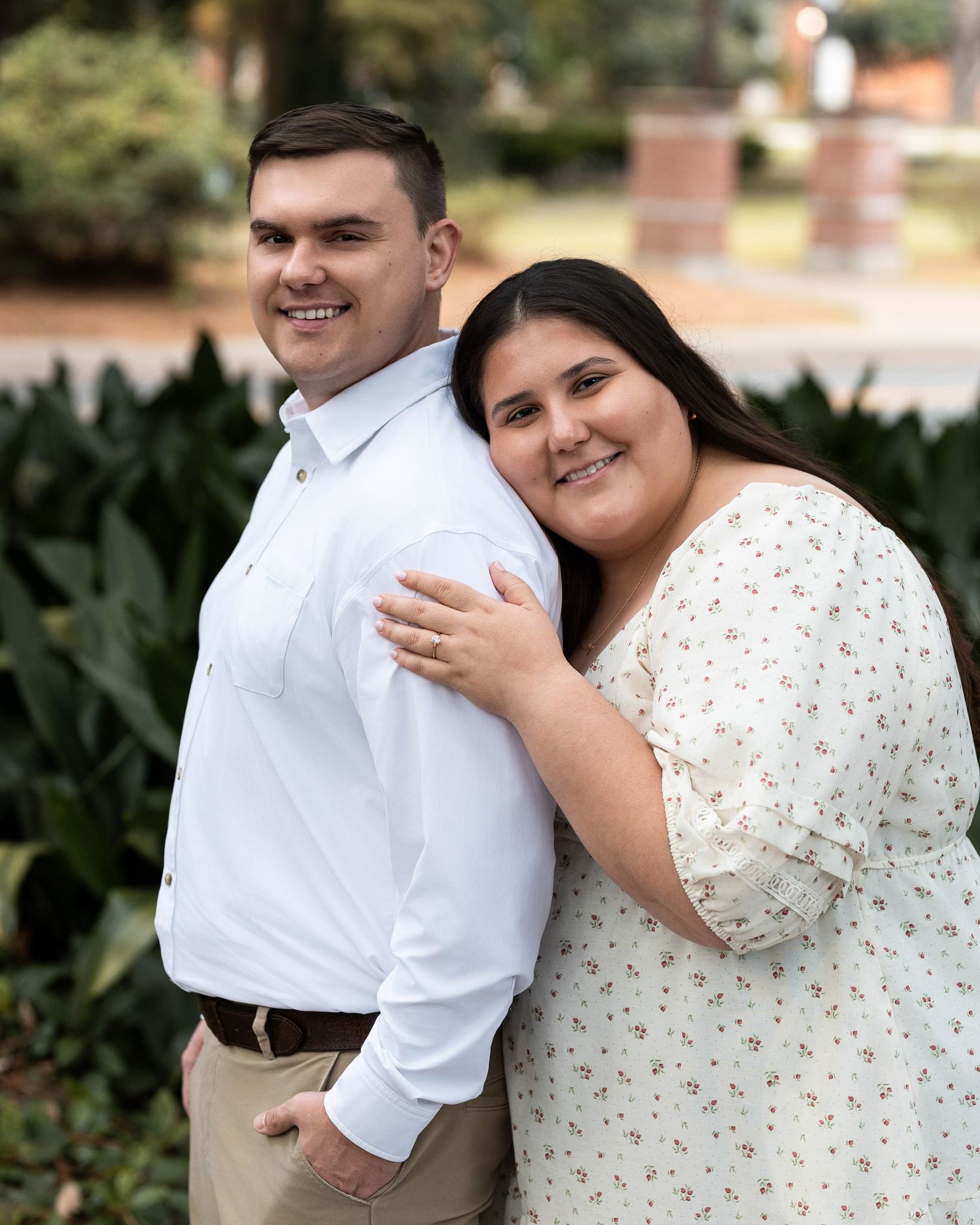 A couple shares joyful moments together outdoors in coordinated white and beige outfits during a photo session.