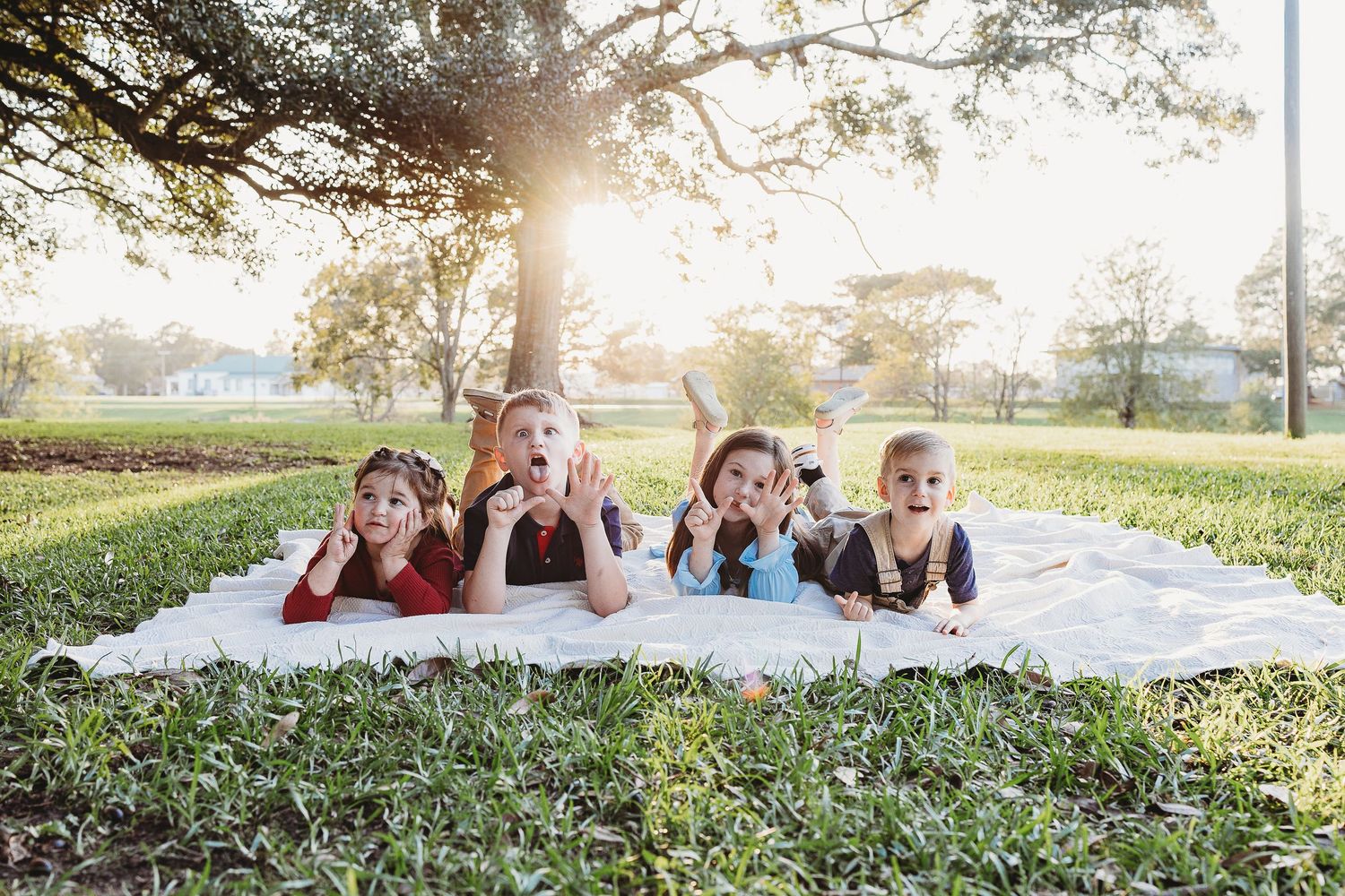 Family lying on grass during sunset photoshoot with dramatic lighting.