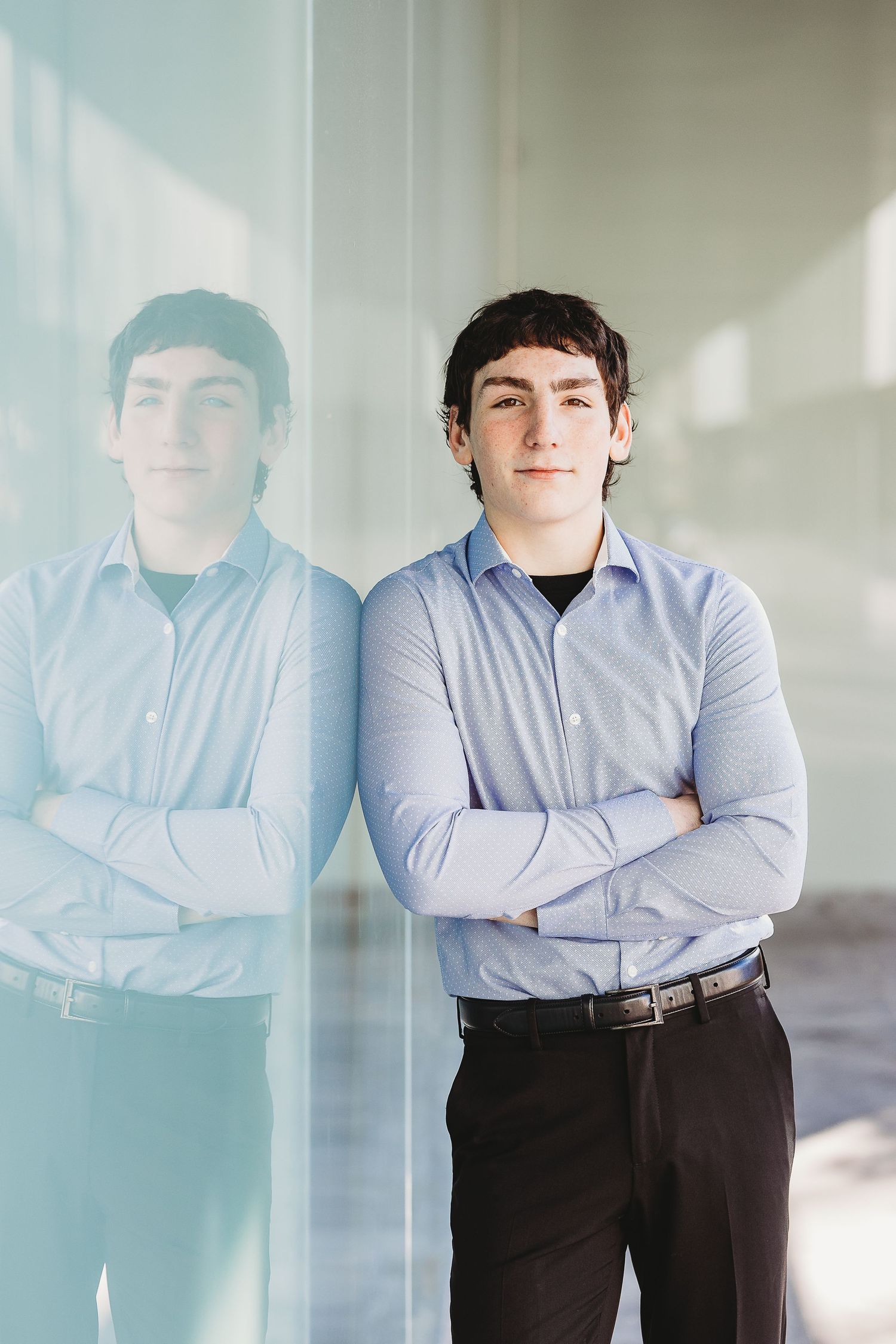 A professional portrait with mirror reflection against a modern wall background.