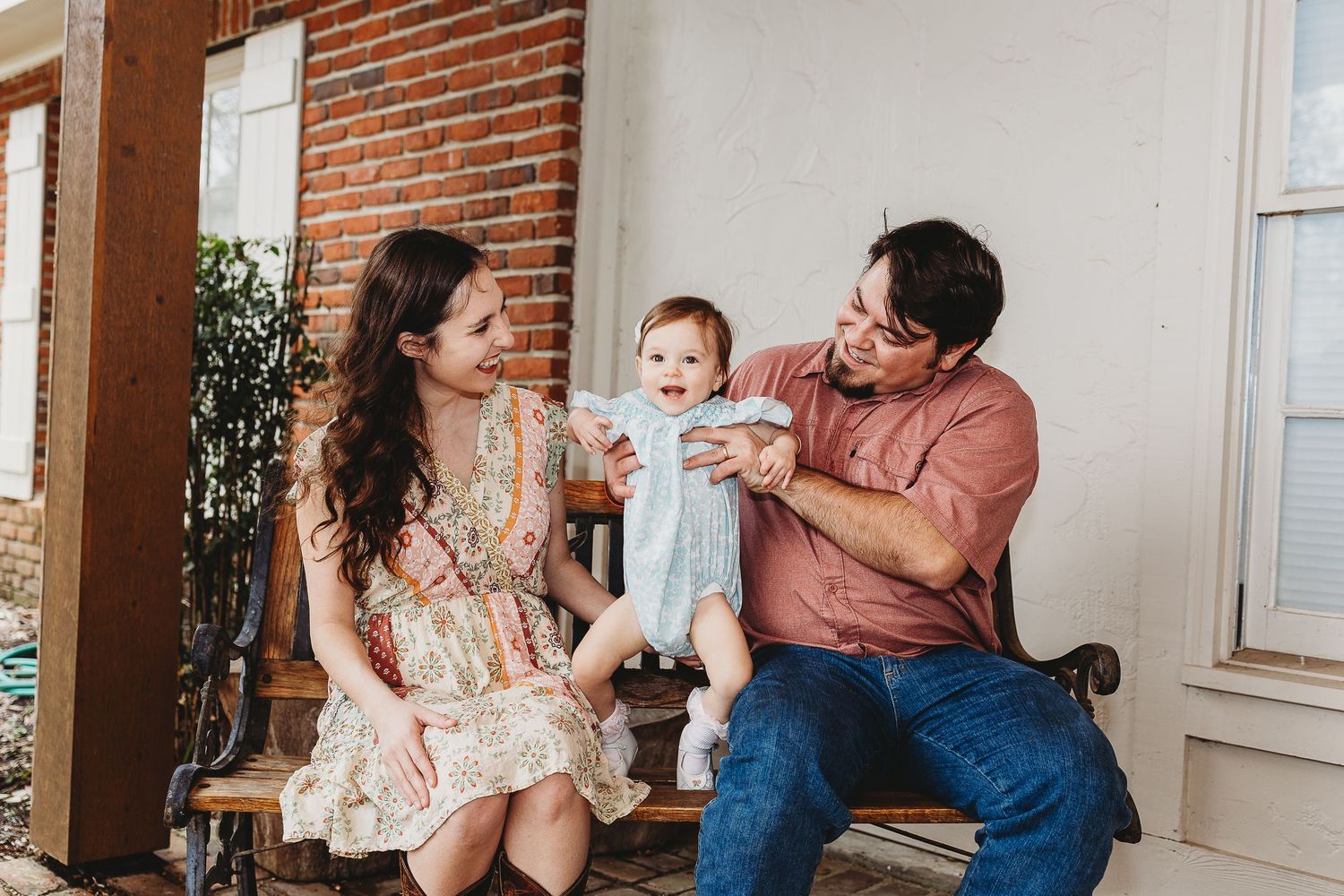 Family moment captured indoors with exposed brick wall background.