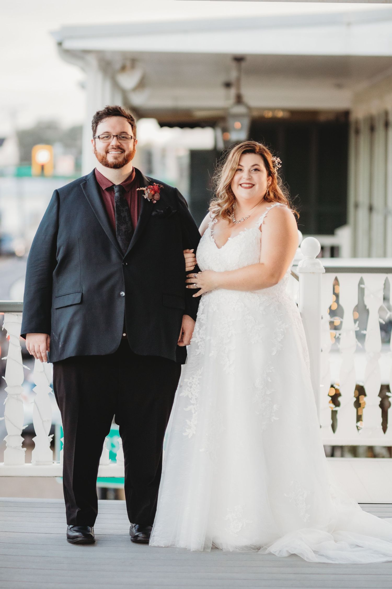 Wedding couple poses along white railings during their special day.