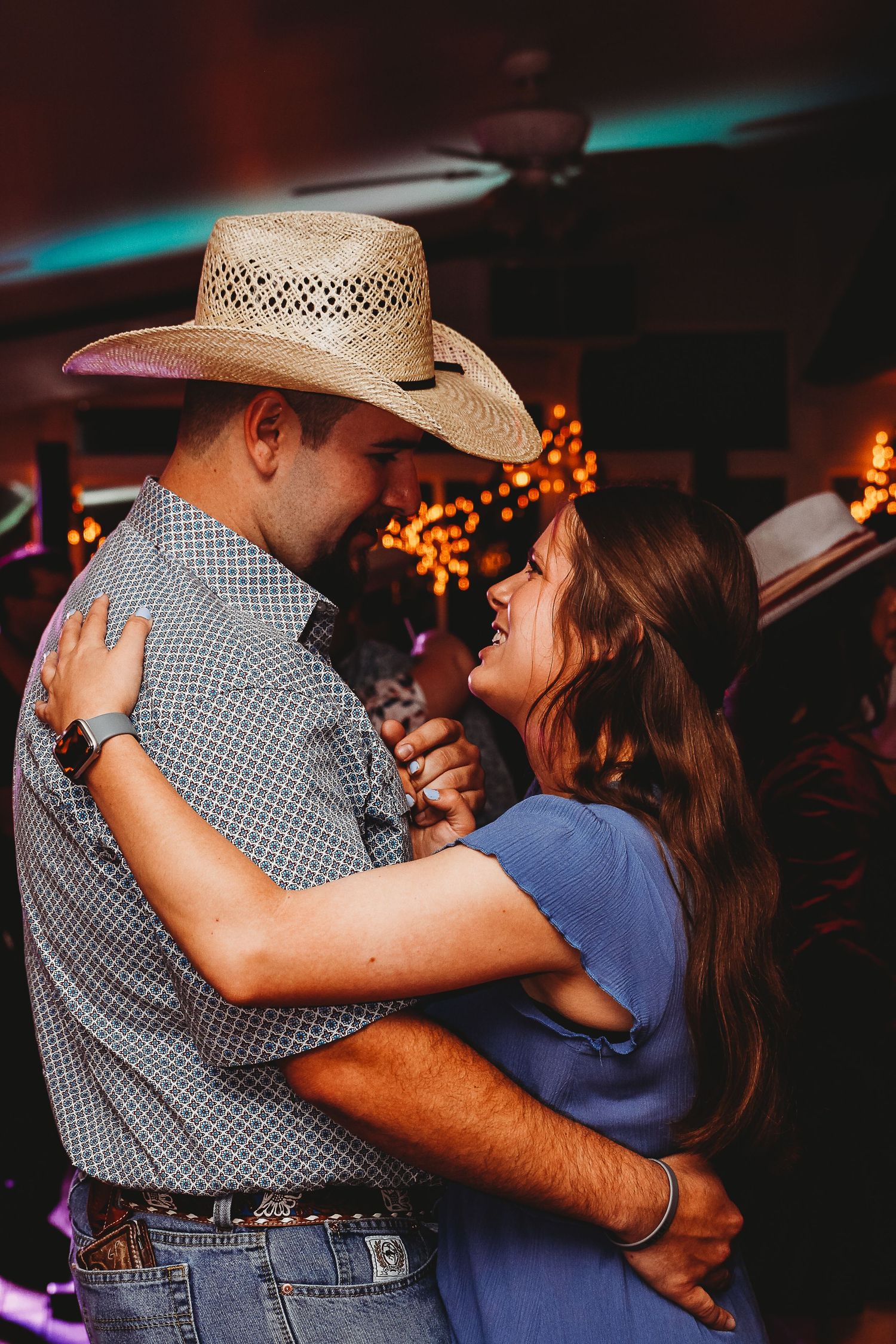 Couples dancing at country western themed wedding reception with string lights overhead.