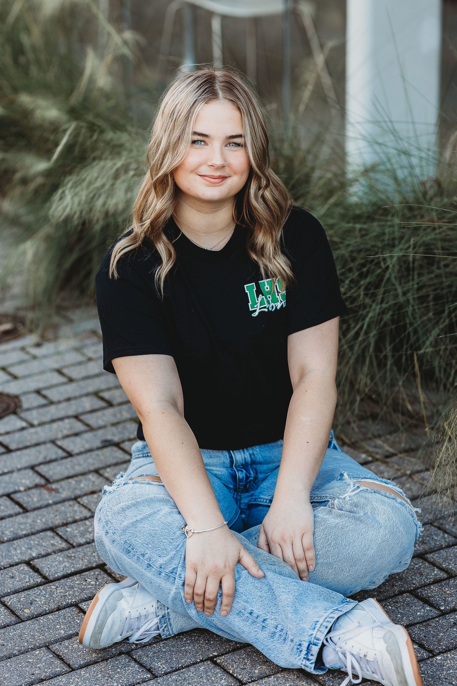 Casual street style portrait with black t-shirt and ripped jeans on brick pavement.