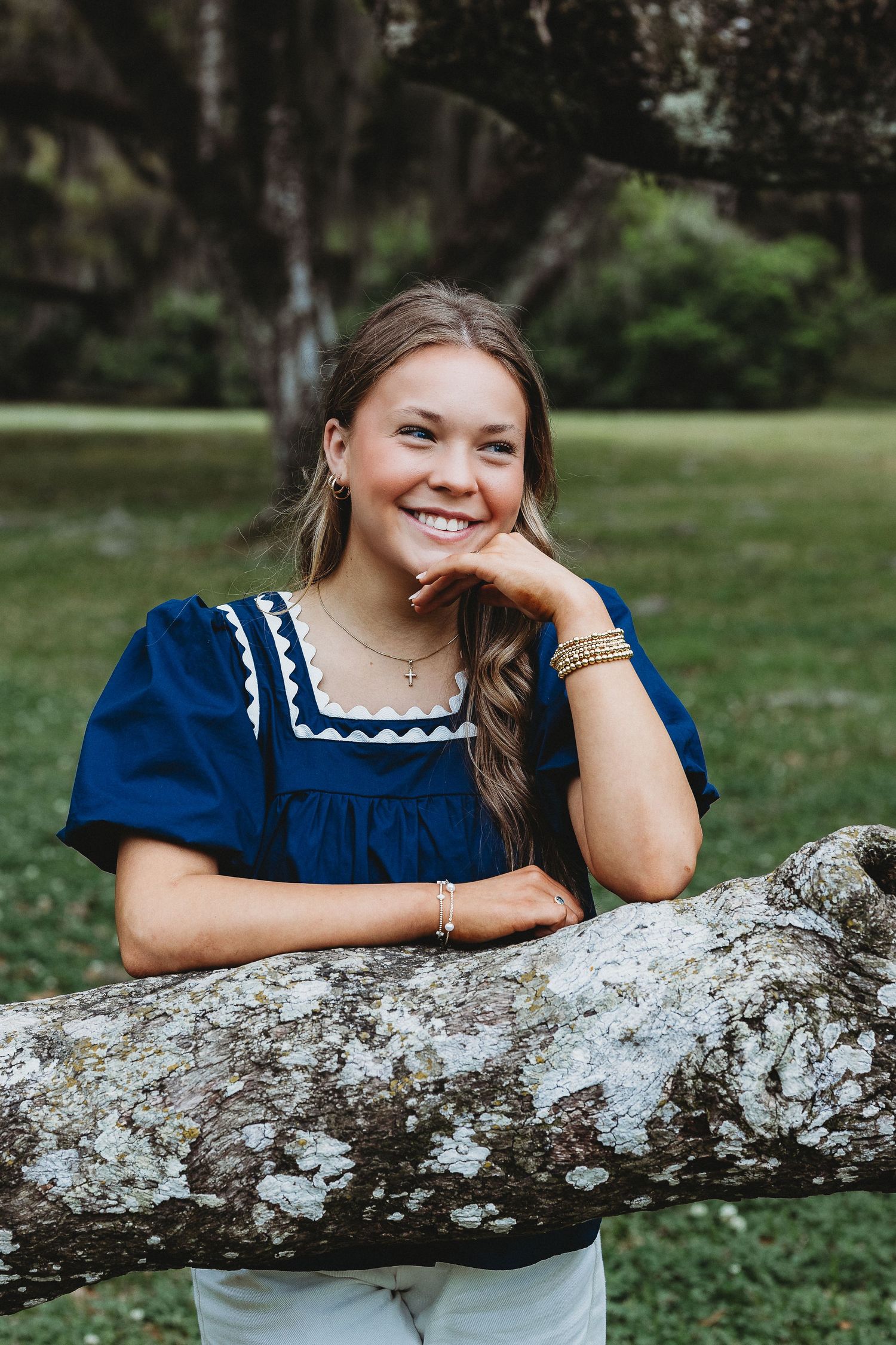 Portrait series showing someone in a blue dress with white trim leaning on a fallen tree.