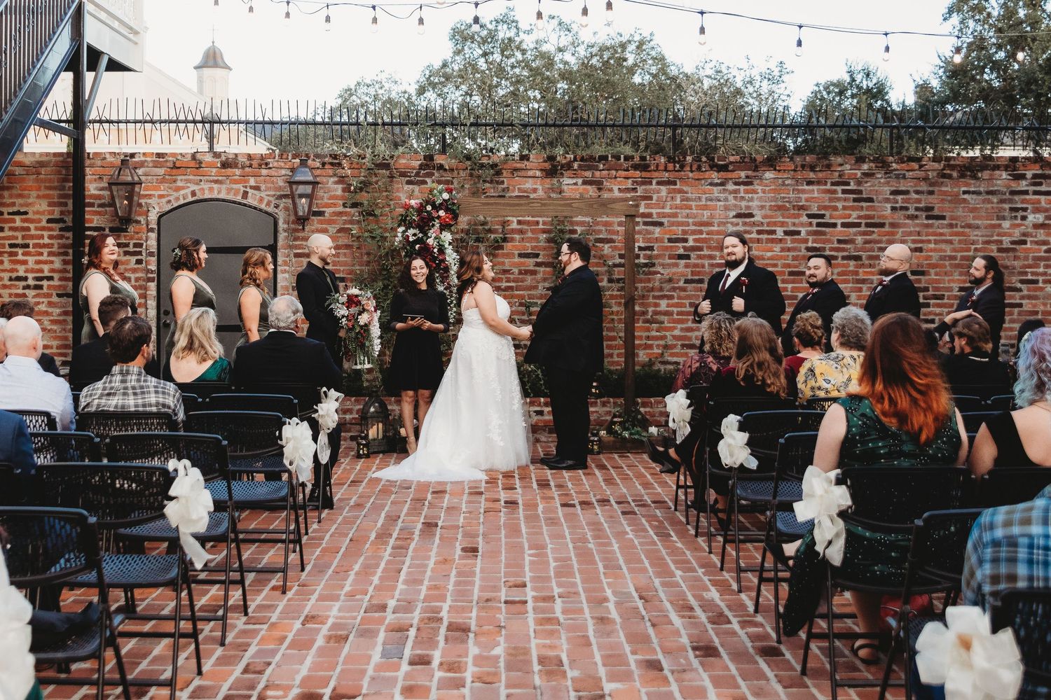 Wedding ceremony setup with rows of chairs and string lights at a rustic brick venue.