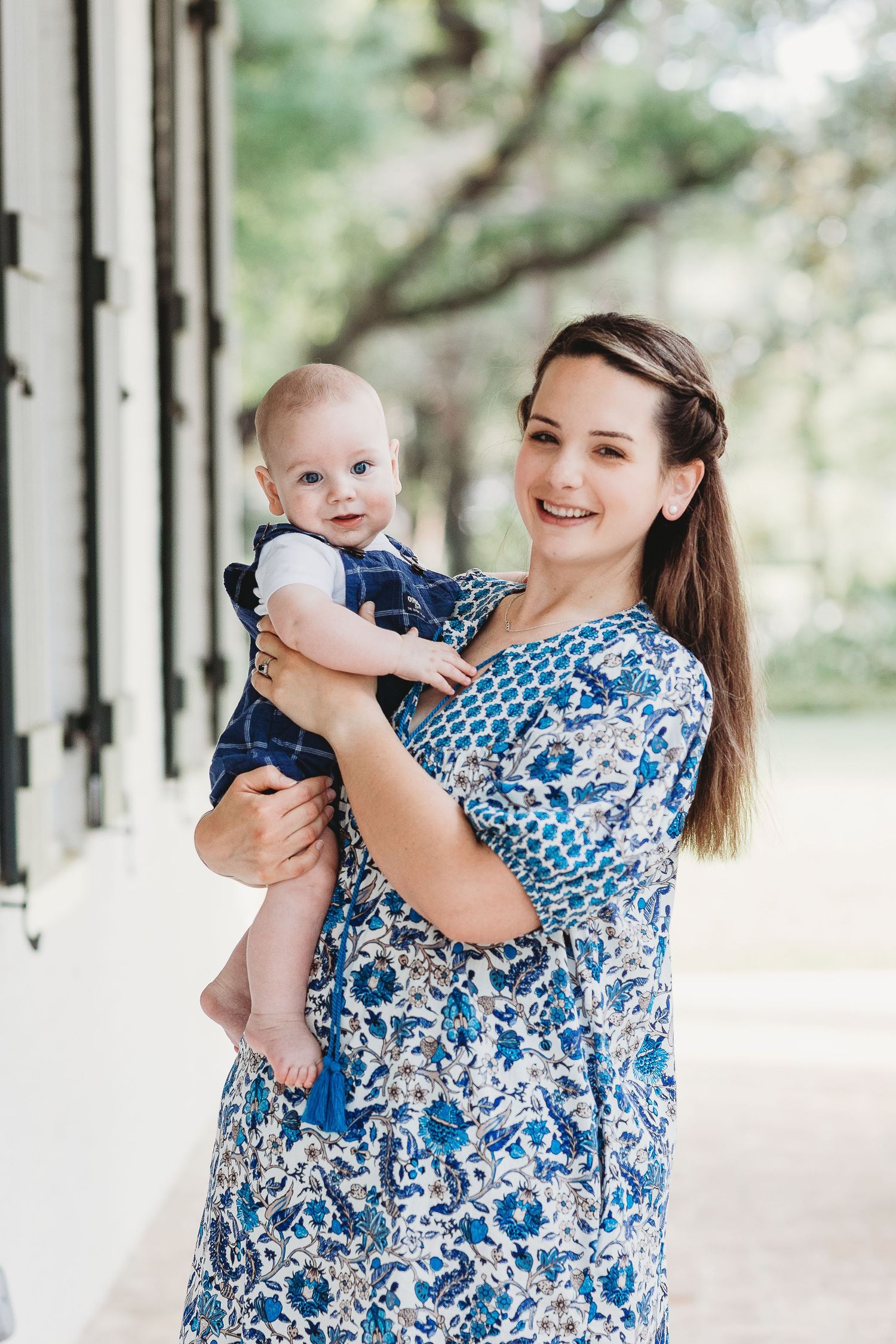 Mother and baby sharing joyful moments under a white columned porch.