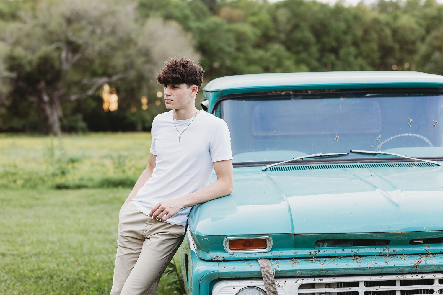 Classic turquoise vintage pickup truck parked in grassy field during outdoor photo session.