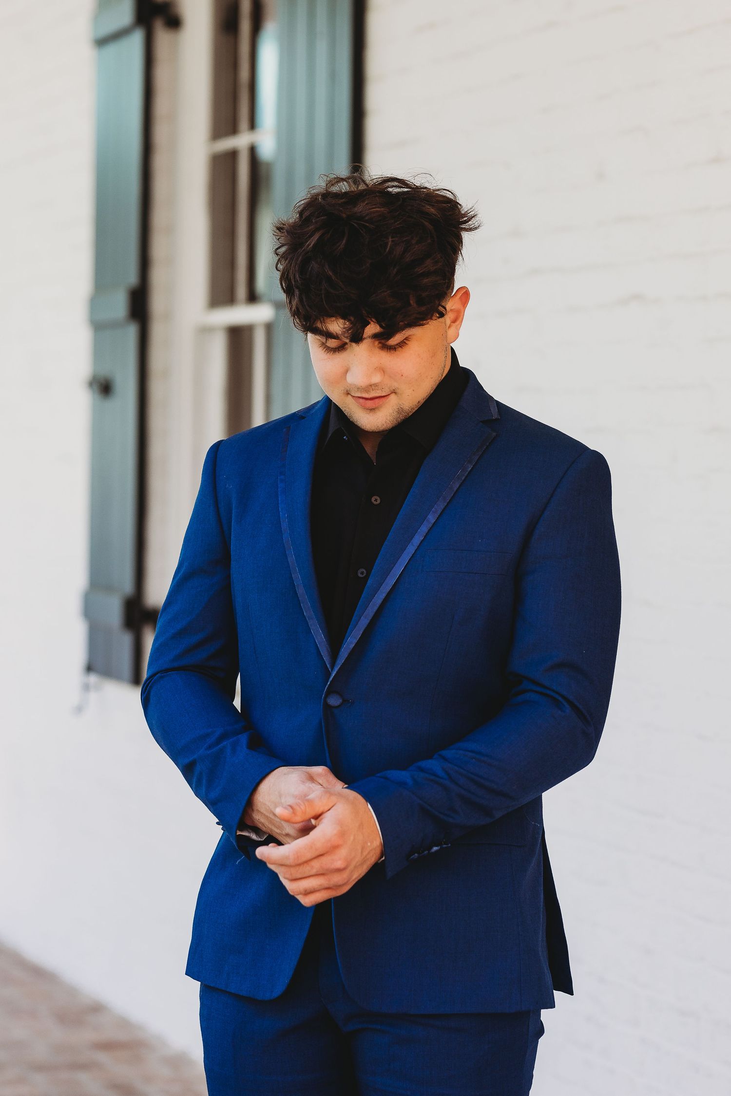 Portrait in royal blue suit jacket against white building exterior.