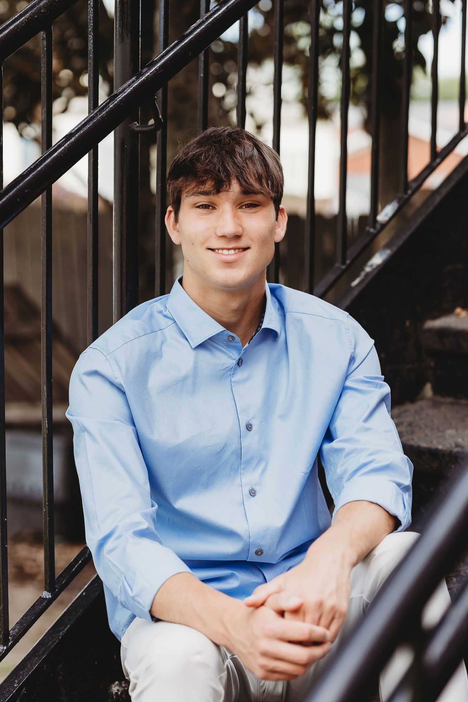 Person in blue shirt sitting on metal stairs with black railing.