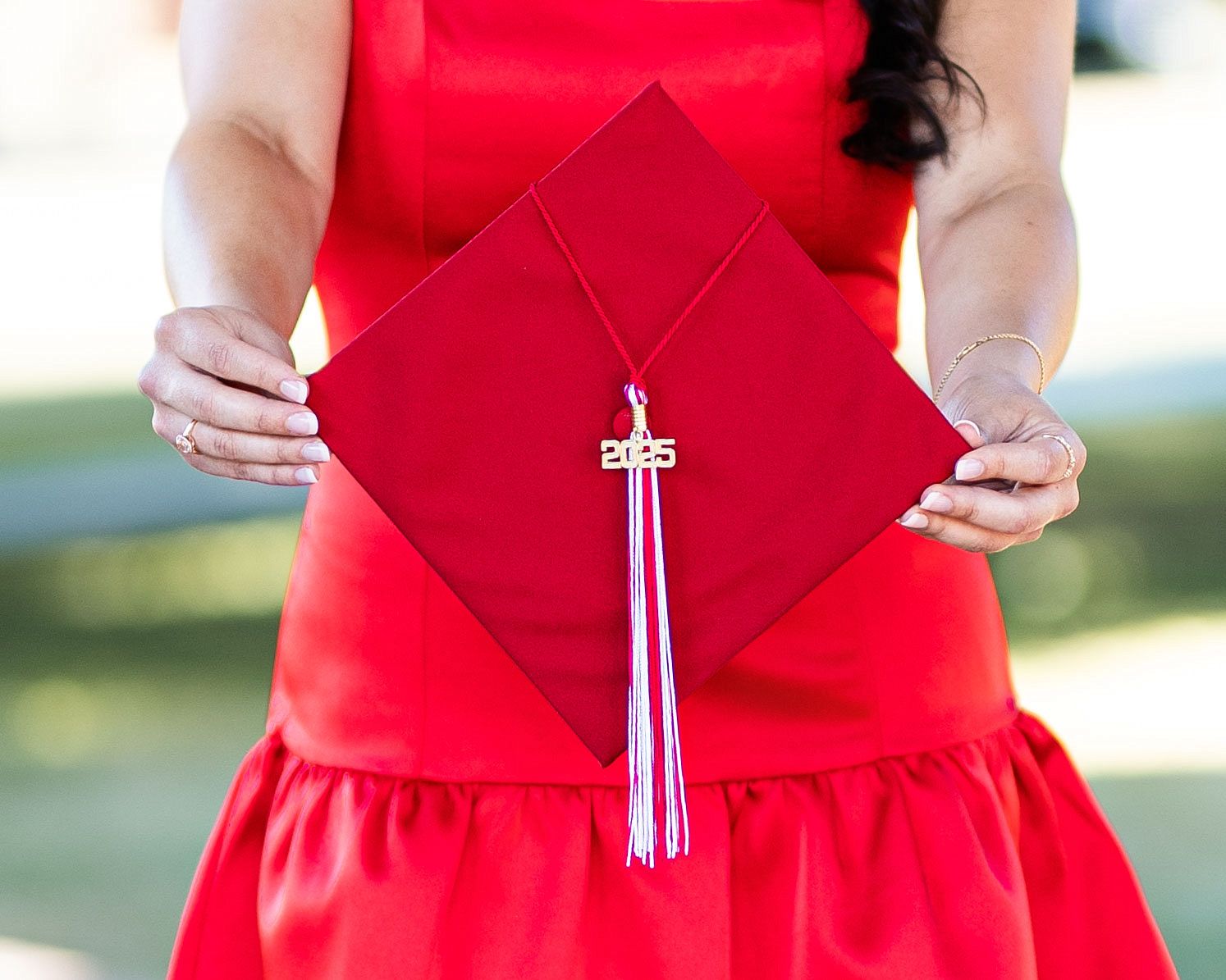 Woman in a vibrant red dress with a flared skirt stands outdoors in natural lighting.