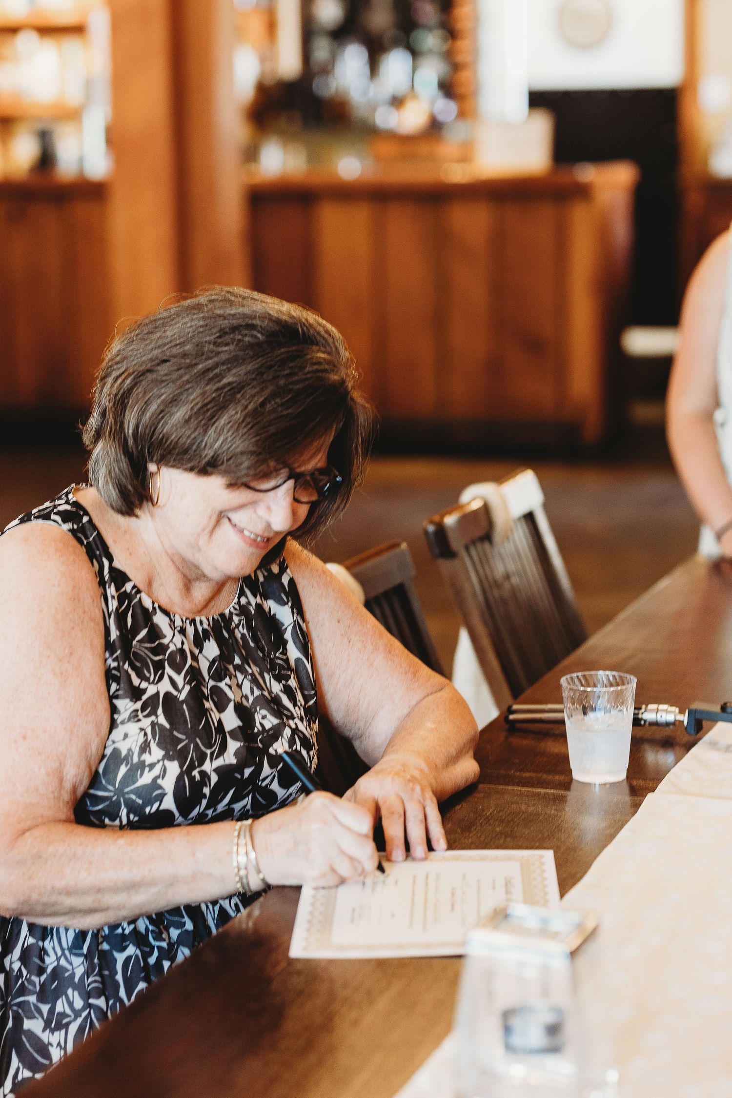 Wedding guest in black and white floral dress signing the guestbook.