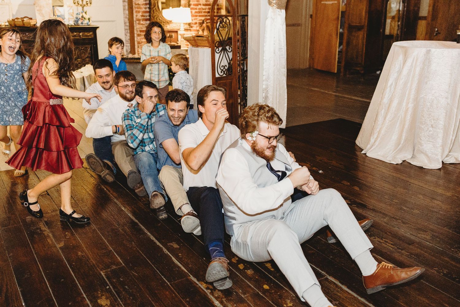 Lively wedding reception with guests dancing and celebrating on a wooden dance floor.