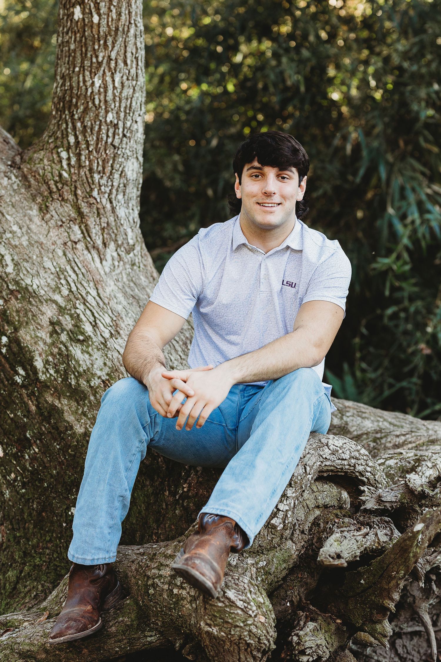 Casual outdoor portrait session on large tree branch in natural lighting.