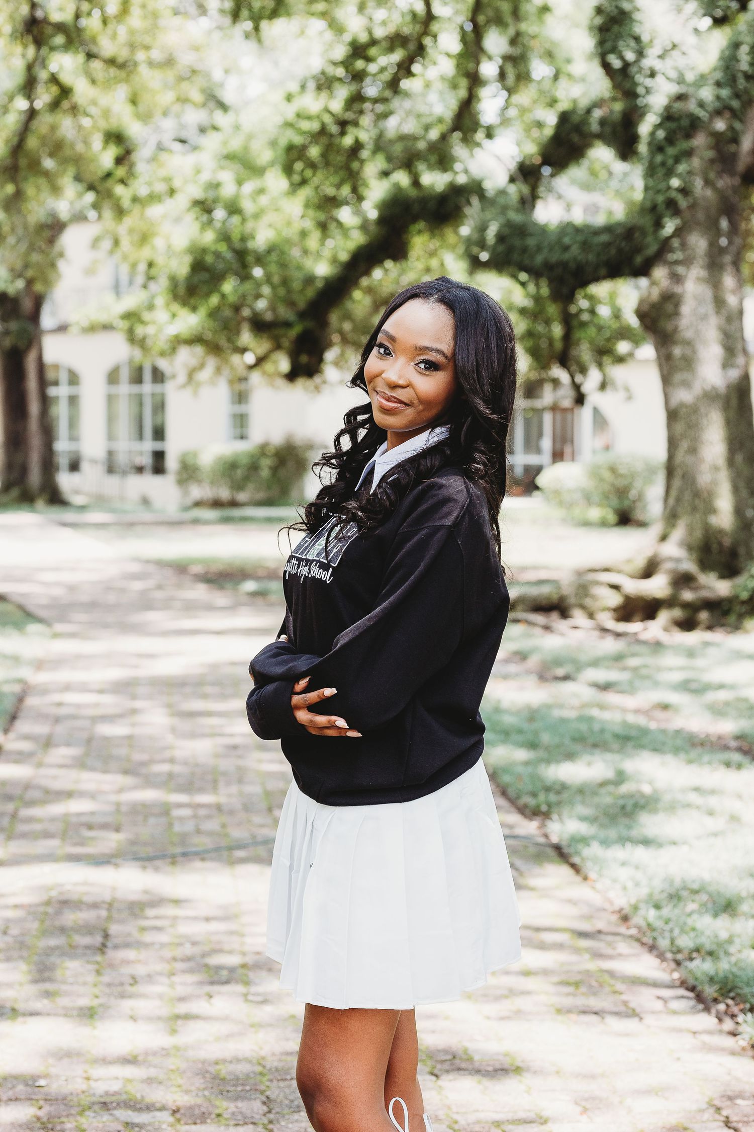 Outdoor portraits in a black sweatshirt and white skirt against a natural backdrop.