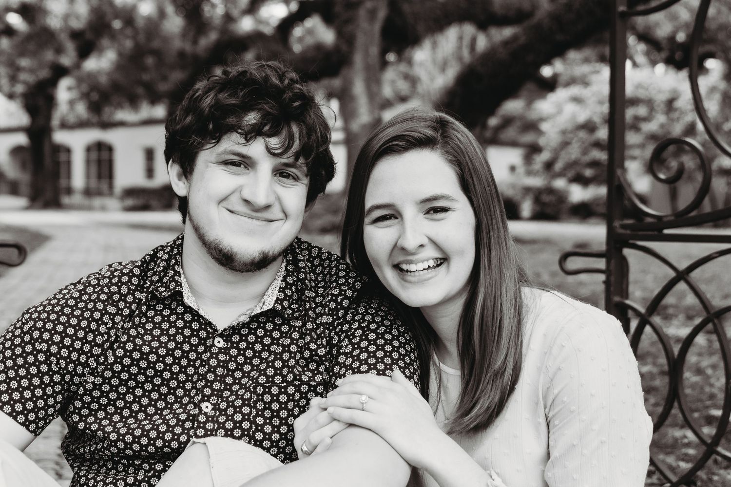 A couple shares a tender moment outdoors in black and white photography.