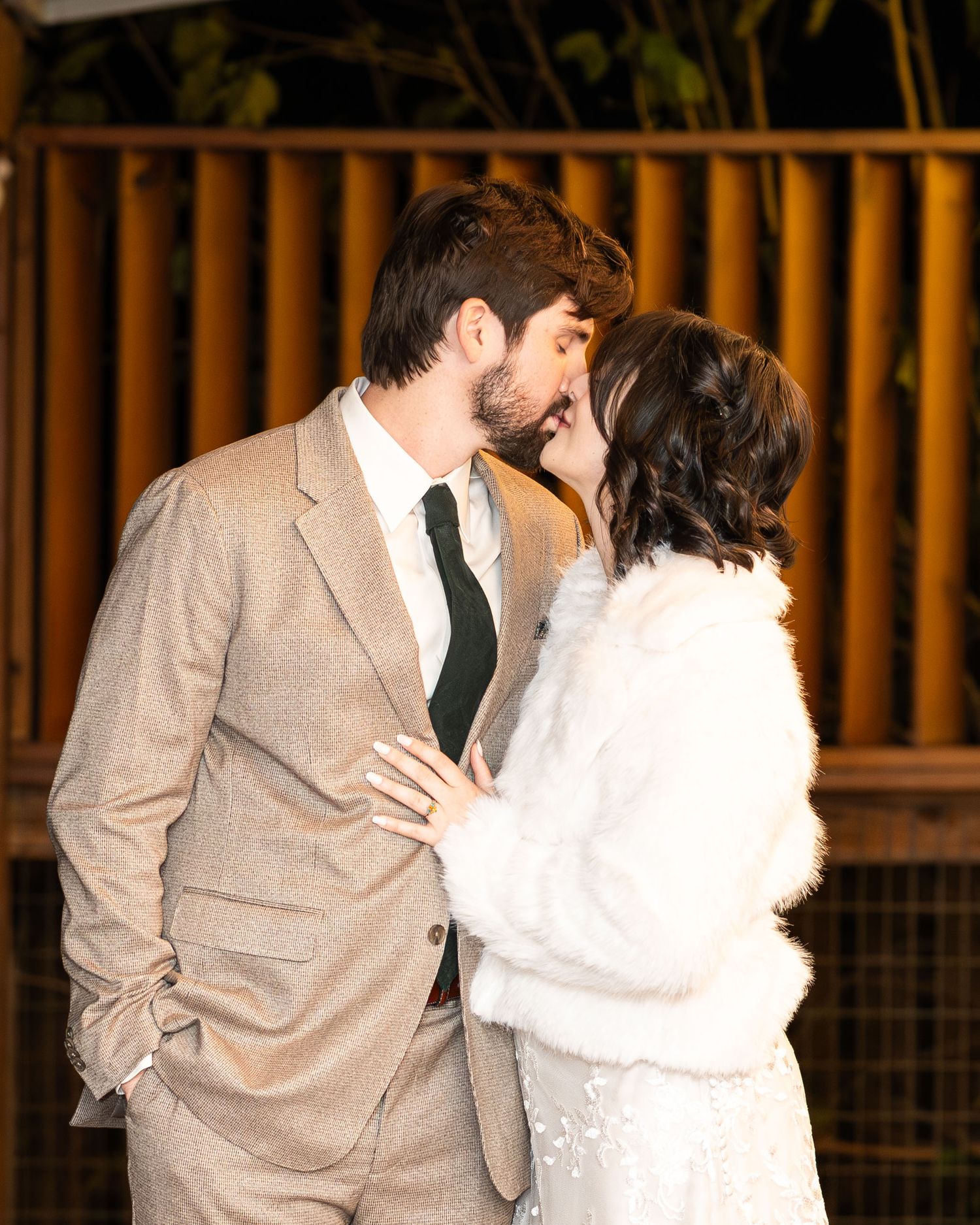 A couple in formal attire share a romantic dance moment at an indoor venue with warm lighting and wooden decor.