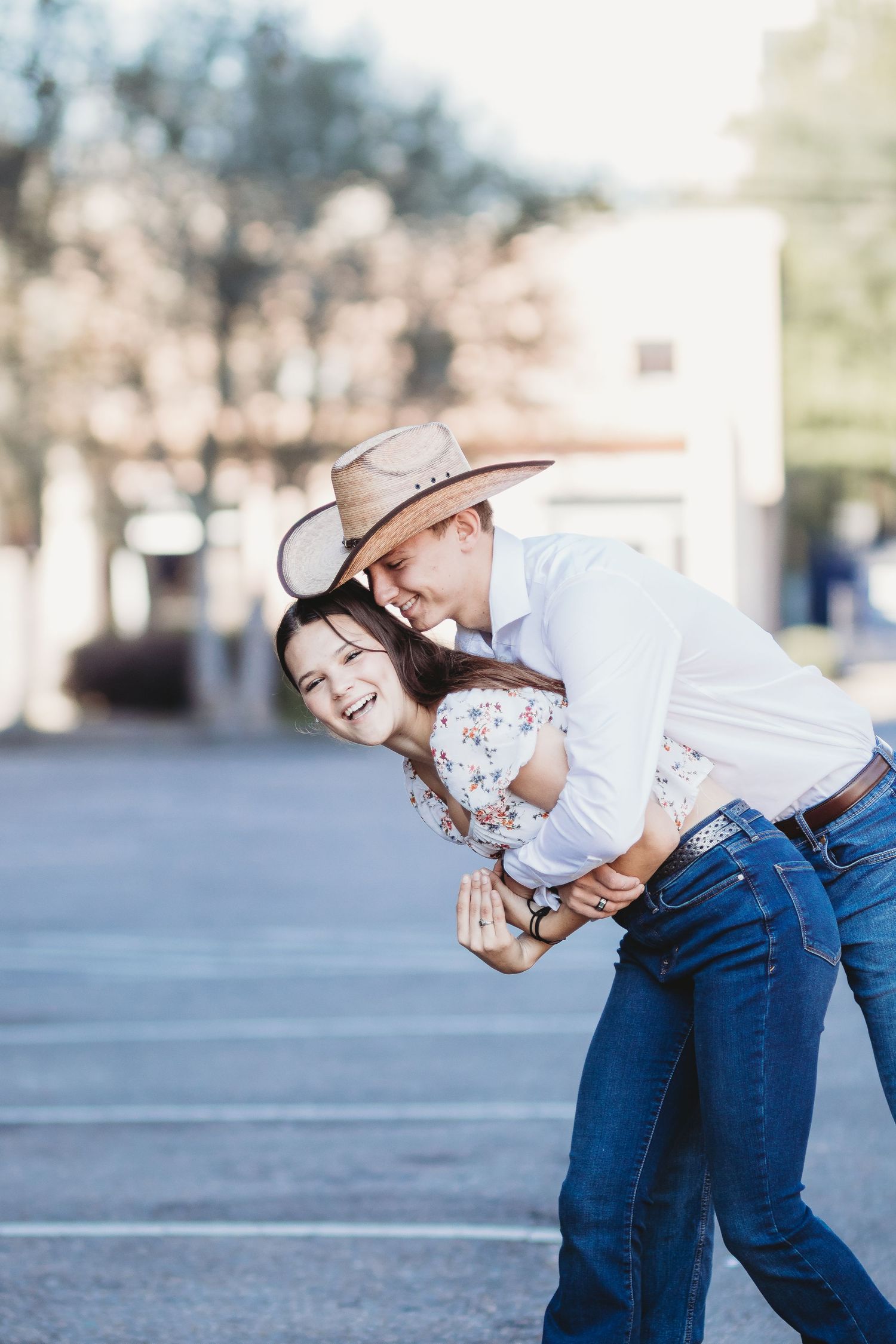 A playful couple in matching denim jeans share joyful moments together in an outdoor setting.