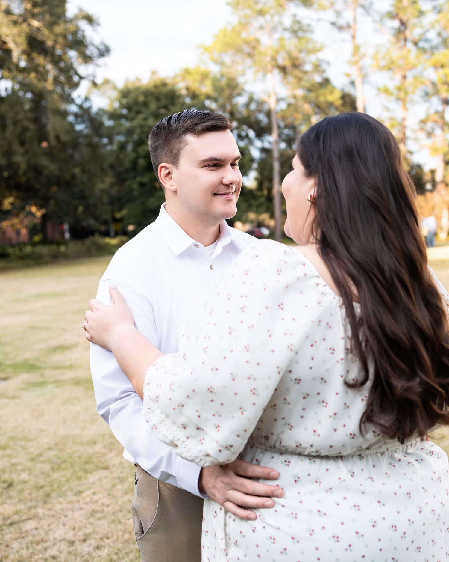 A romantic outdoor photoshoot featuring a couple embracing and laughing together in a natural setting.