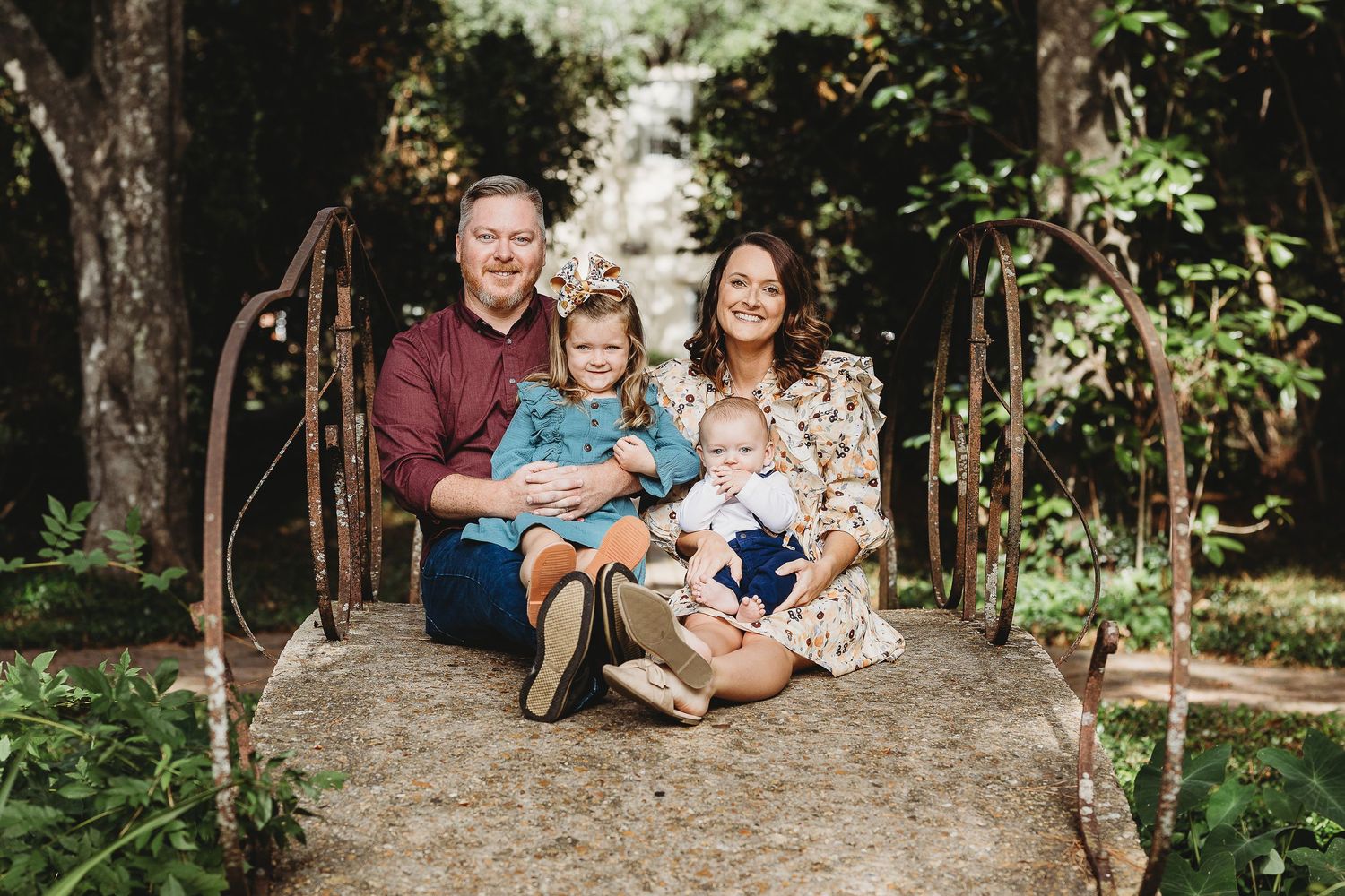 Outdoor family portrait session in wooded area with natural lighting.