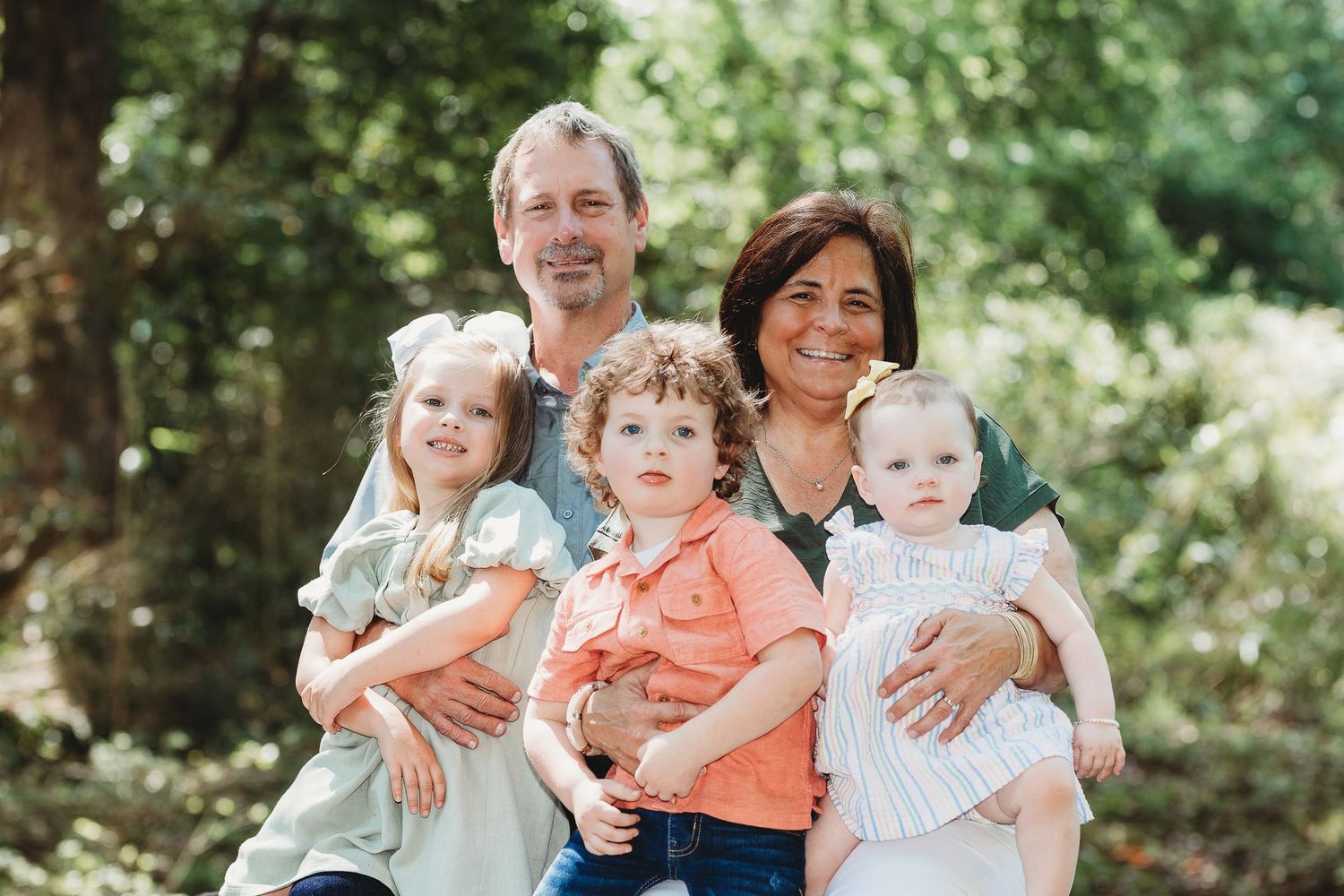 Casual family portrait session outdoors with natural greenery backdrop.