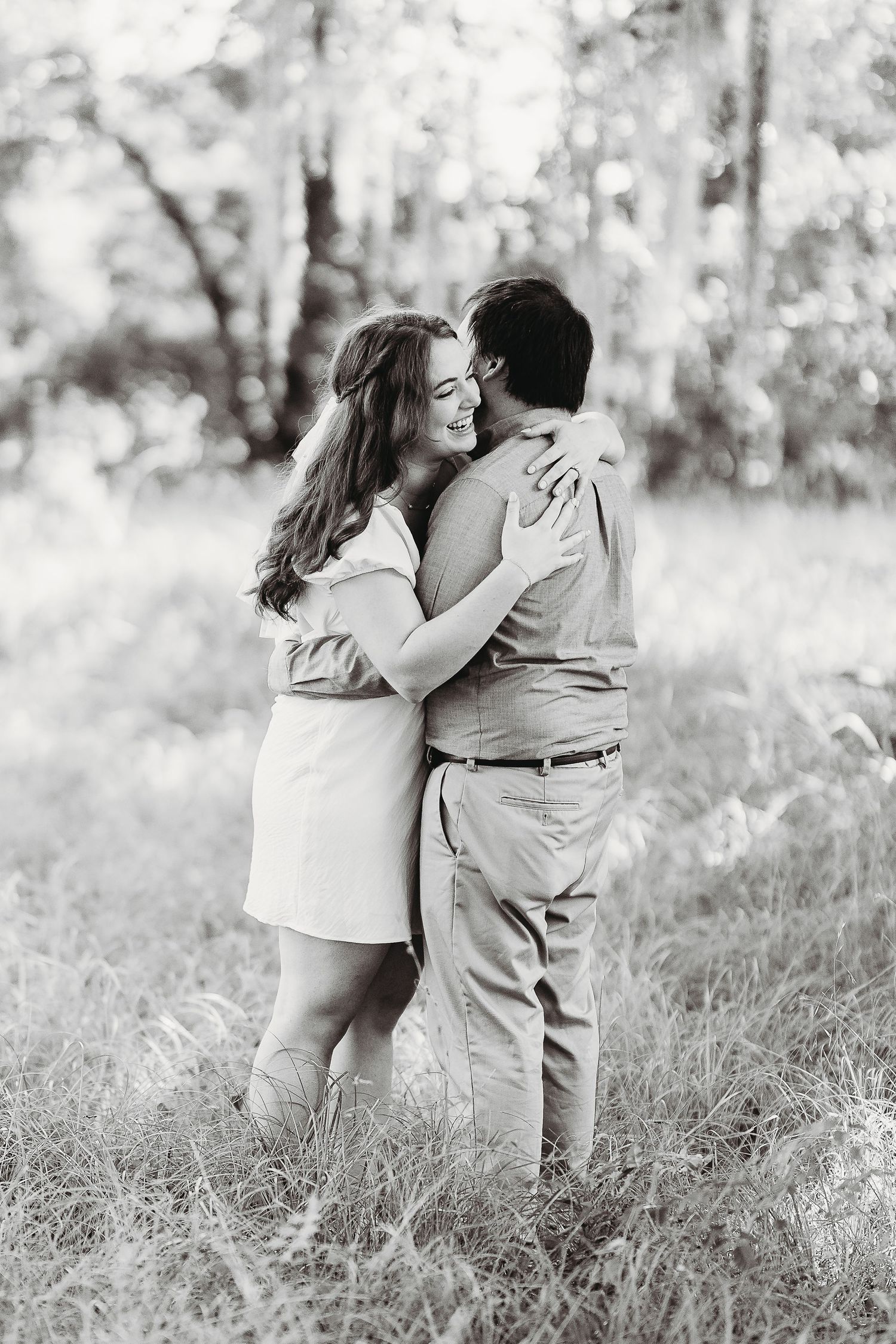 A black and white photo captures an intimate moment between a couple in a natural setting.