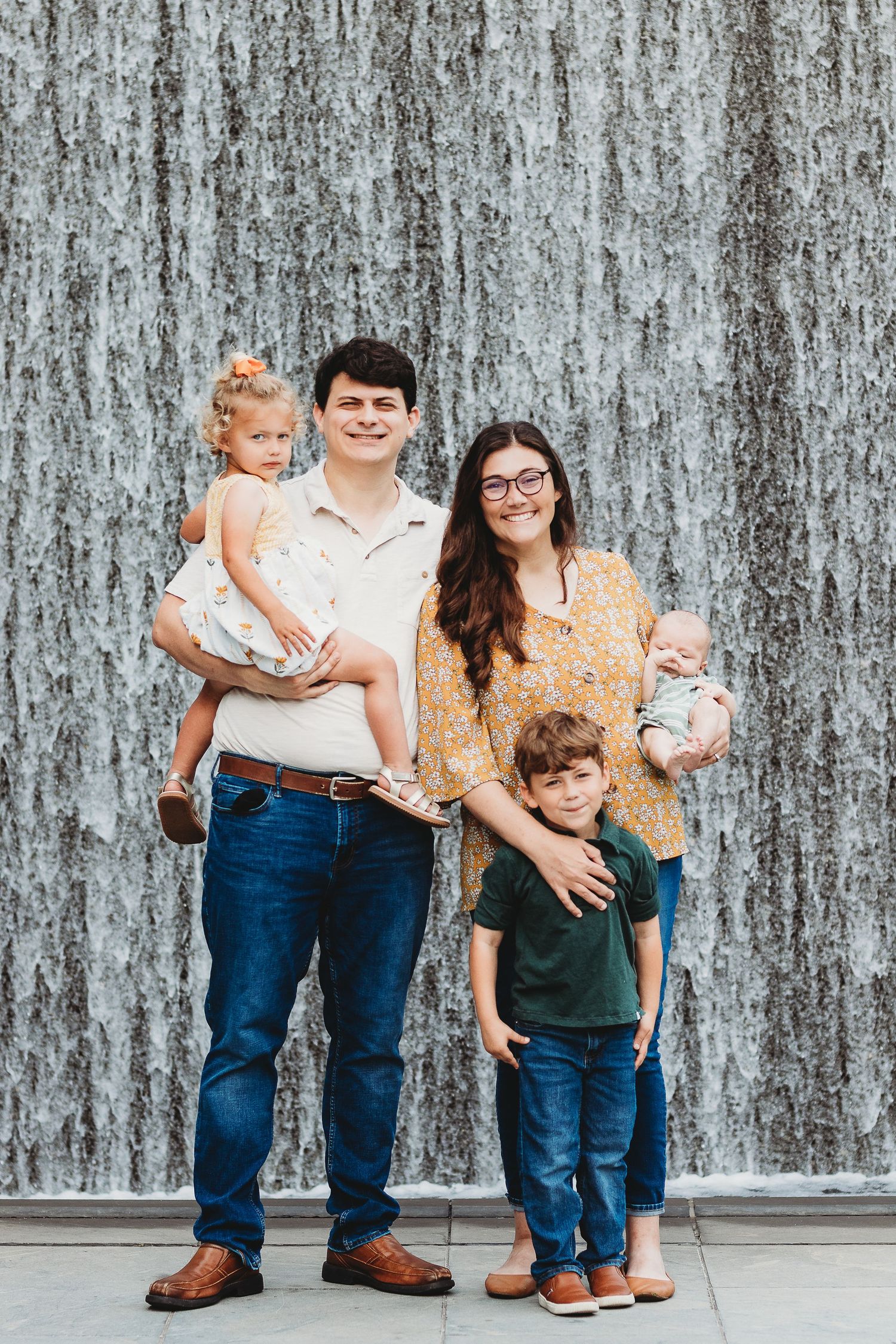 A family of four poses against a textured gray wall background.