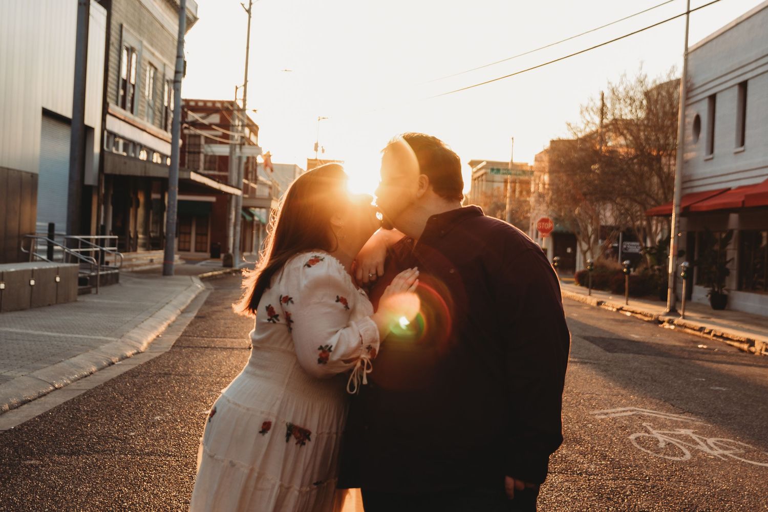 A couple embraces during golden hour on a quiet street.