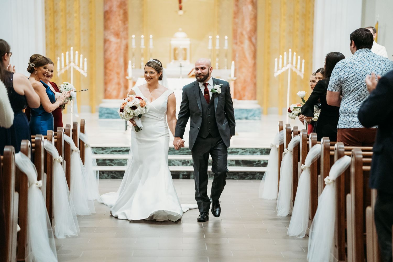 Wedding ceremony in progress inside an ornate church with marble columns and golden decor.