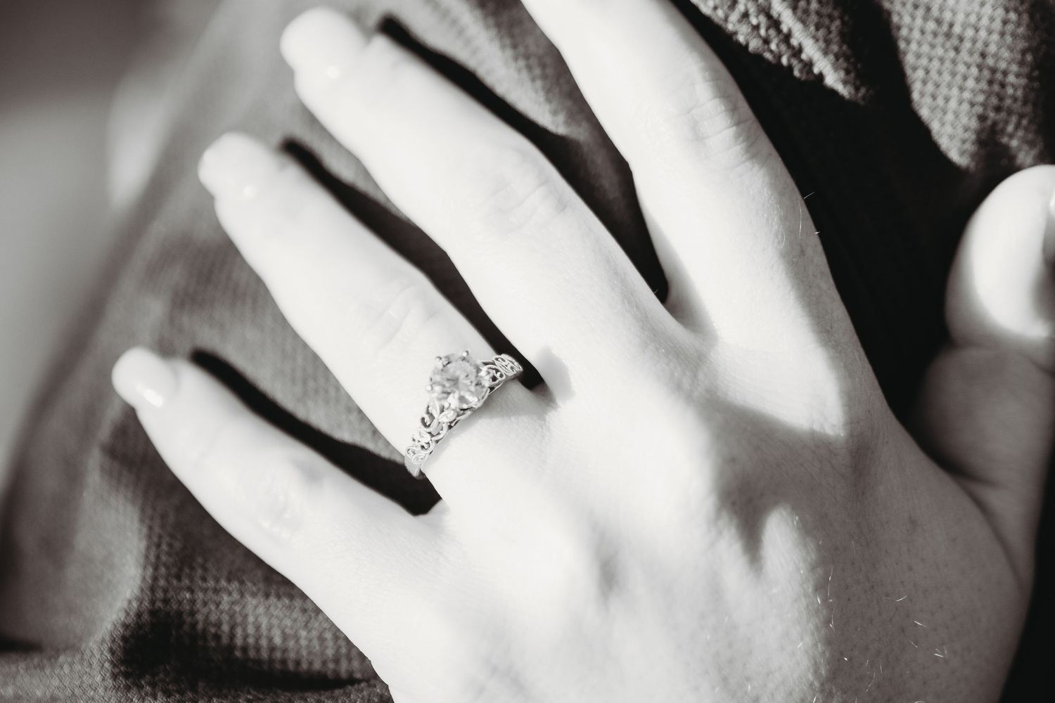 Close-up black and white shots of engagement rings on hands.