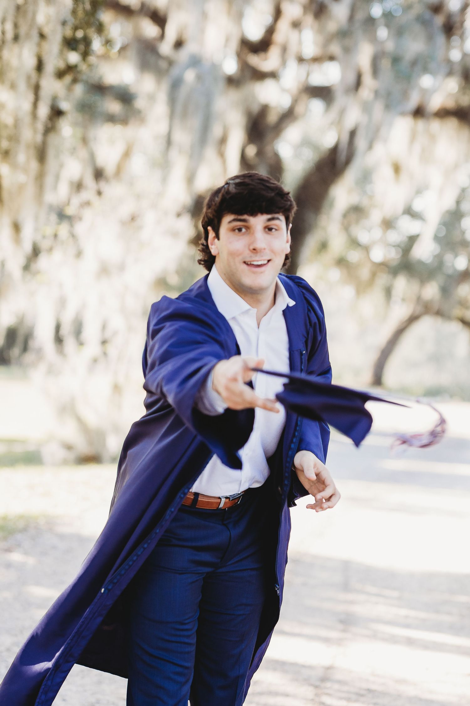 Graduation photo series showing playful poses in blue cap and gown.