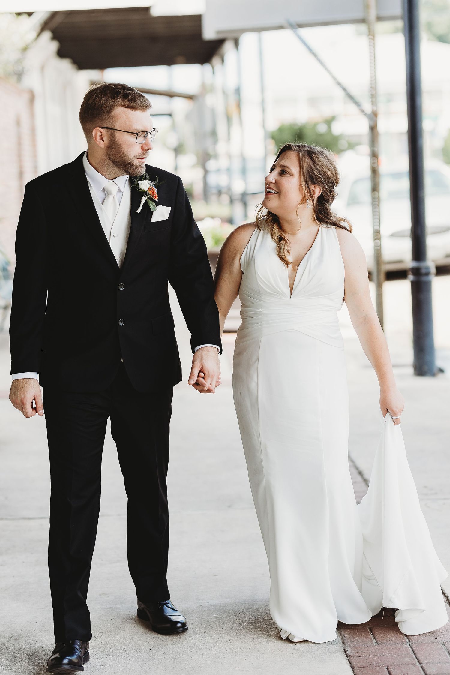 Candid wedding portraits under covered walkway with white columns.