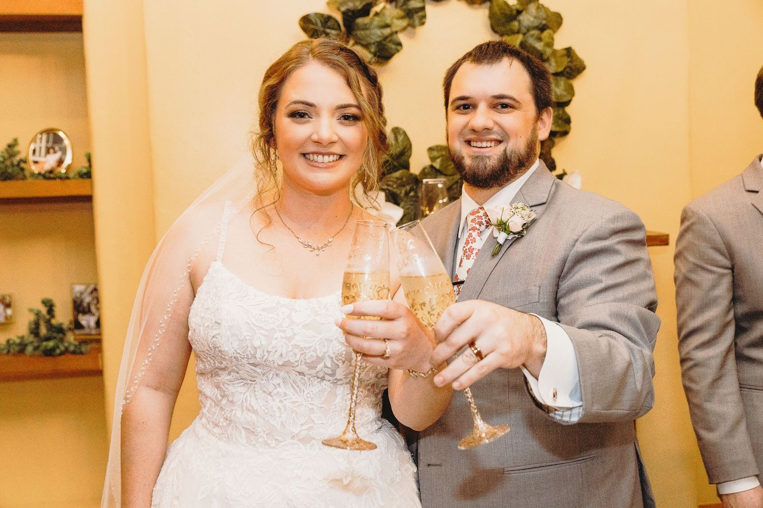 Newlyweds celebrate by their elegant white wedding cake decorated with fresh flowers.