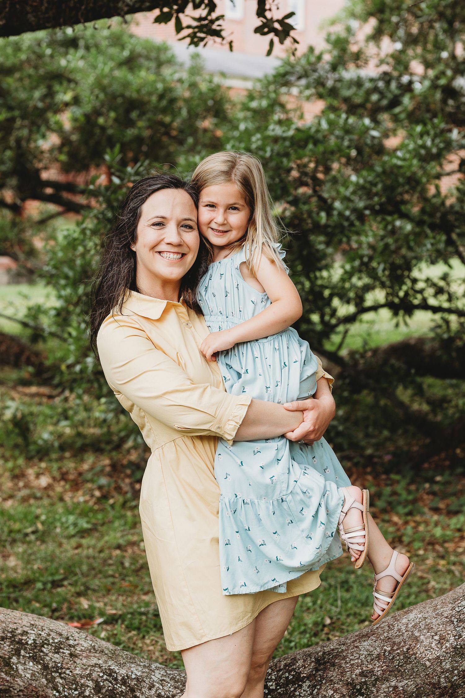 Two people share a joyful embrace while posing near trees outdoors.