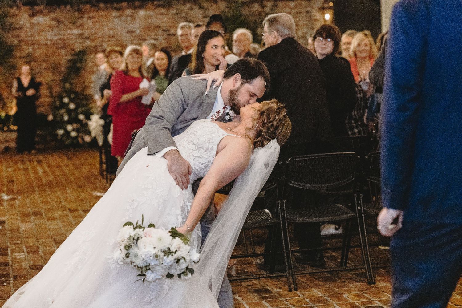 A romantic wedding couple shares an intimate moment during their reception in a rustic brick-walled venue.