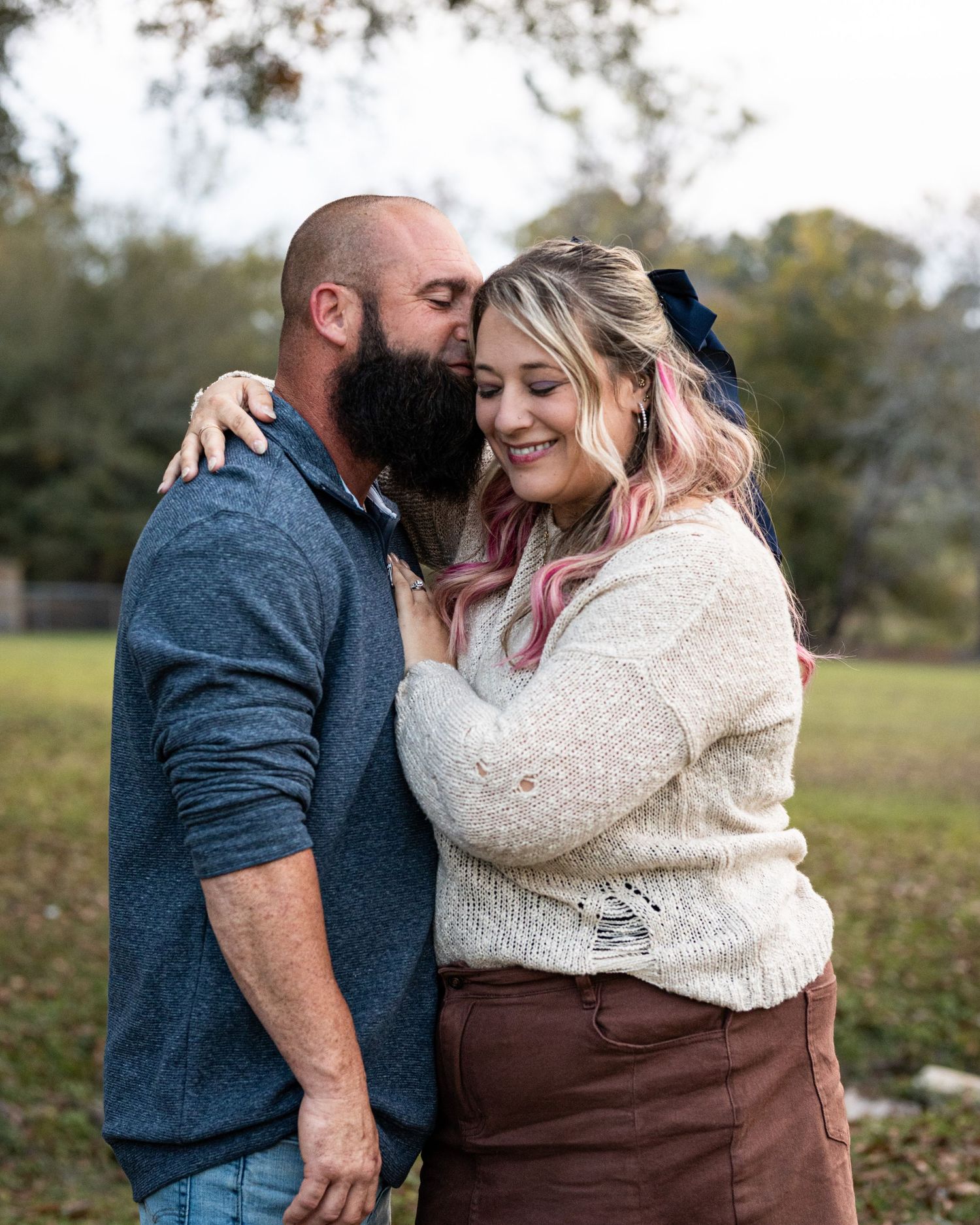 Romantic couple sharing intimate moments in a field during autumn, wearing coordinating blue and cream outfits.