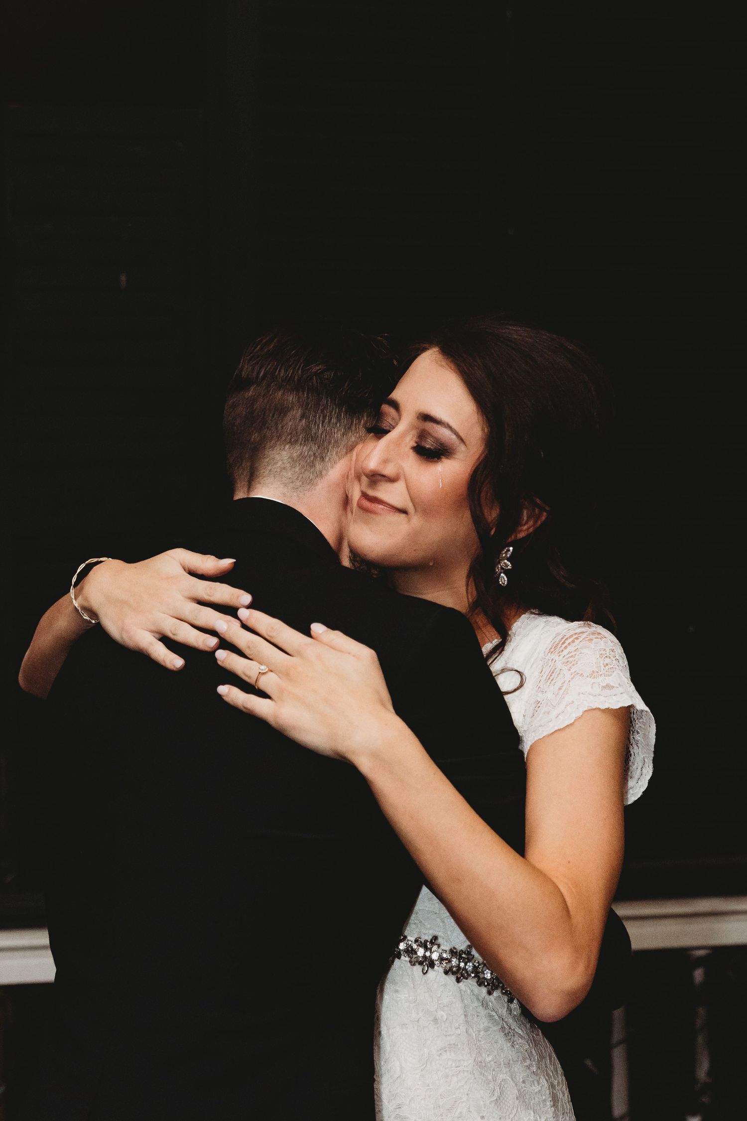 Intimate black and white wedding photos capture emotional embraces between newlyweds.