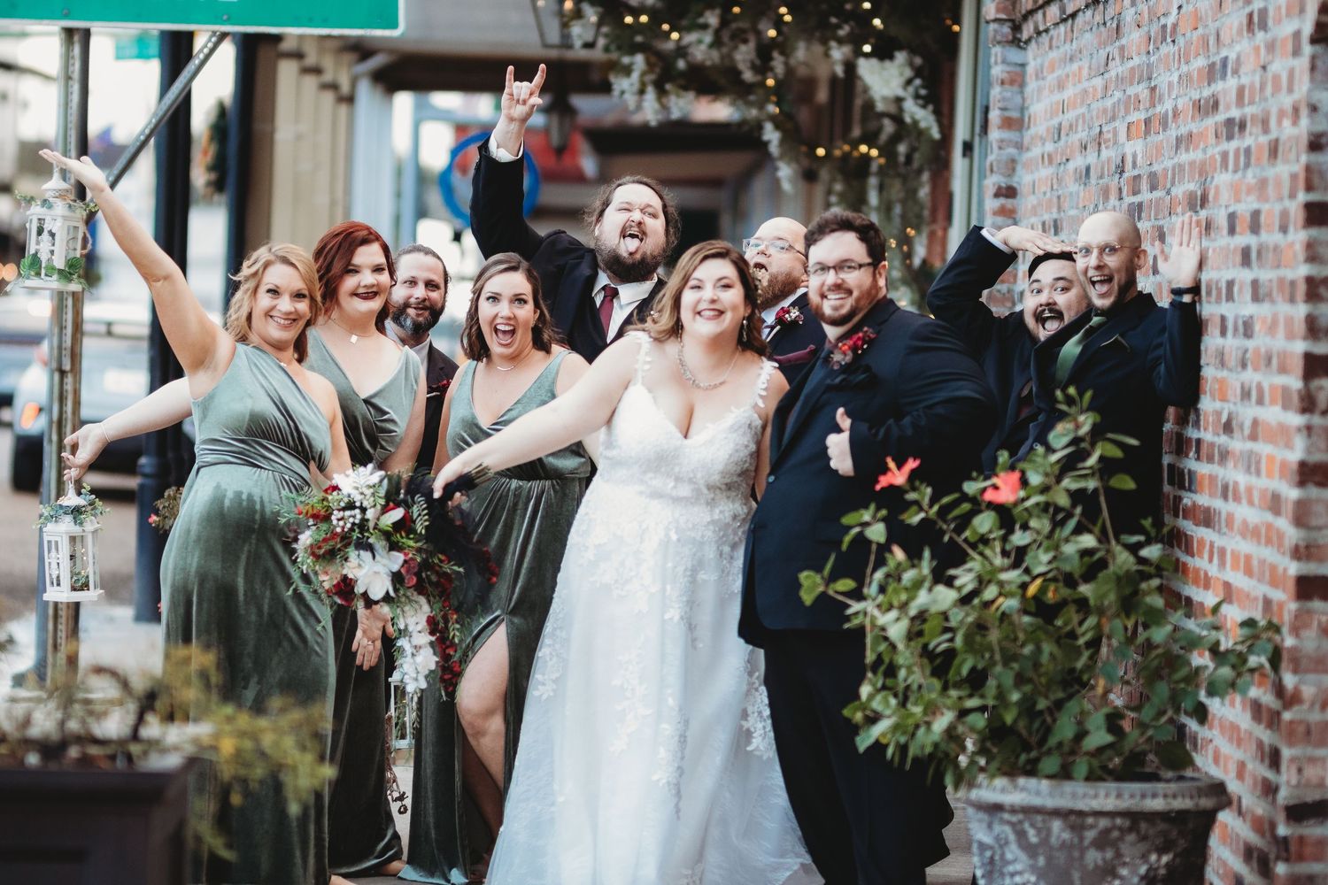 Wedding party celebrates with laughter and smiles outside a brick venue.