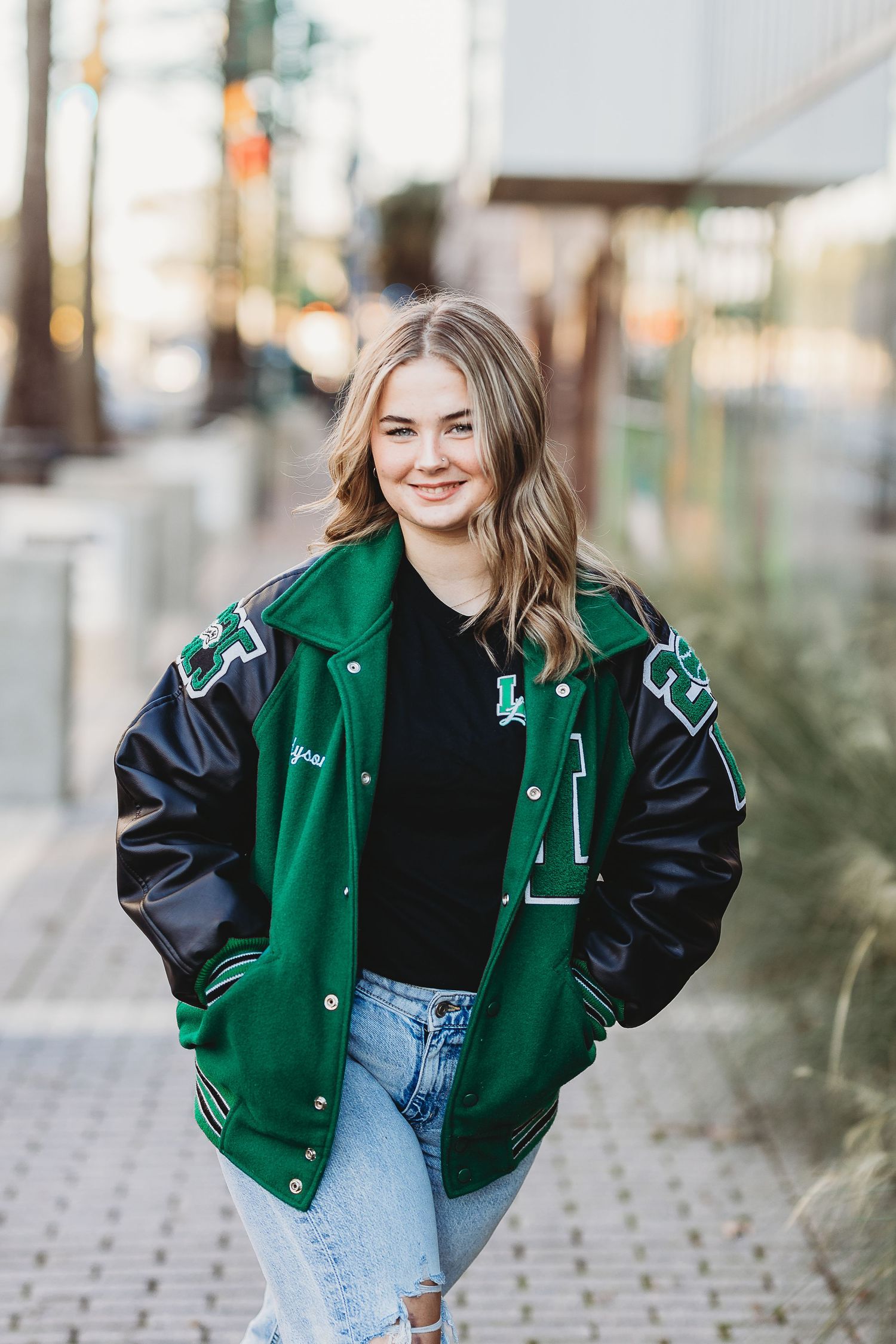 Athletic letterman jacket in emerald green paired with casual denim look.