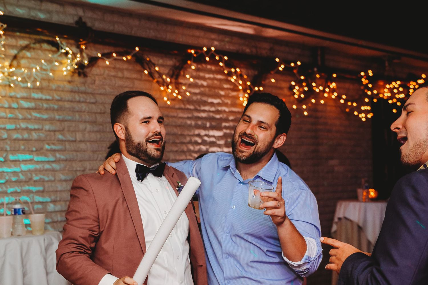 Wedding reception party with string lights creating a warm ambiance in rustic brick venue.