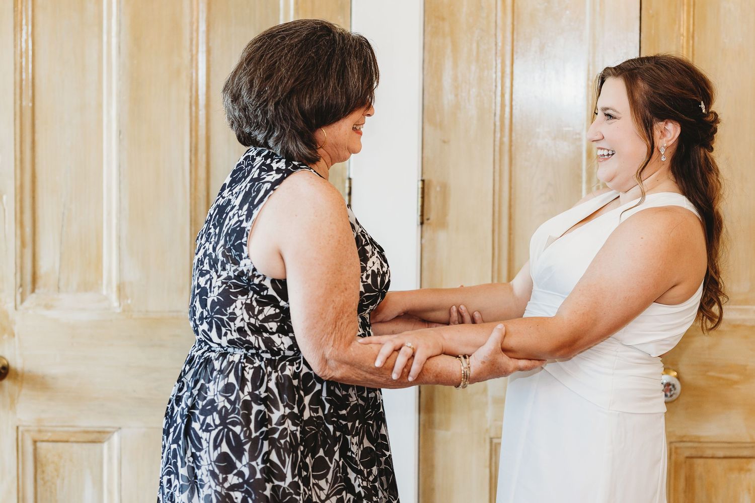 Wedding party interacting in front of wooden paneled wall.