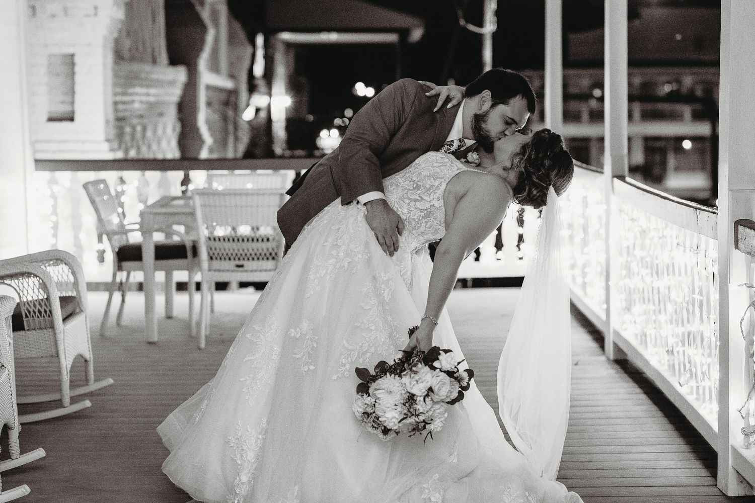 Romantic wedding portraits taken on a white porch at night with soft lighting.